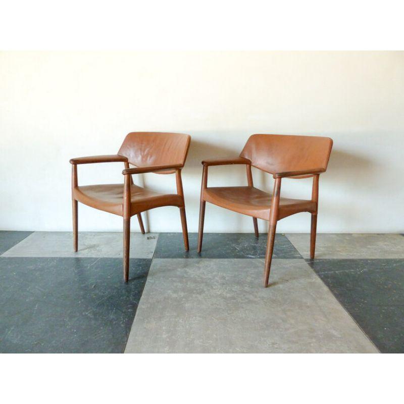 Pair of brown leather arm chairs by Ejner Larsen & Aksel Bender Madsen, Model 1924/S designed in 1954. The chairs include round wengé legs and painted brown leather upholstered on seat, back, and armrests. Made and marked with plaque by cabinetmaker