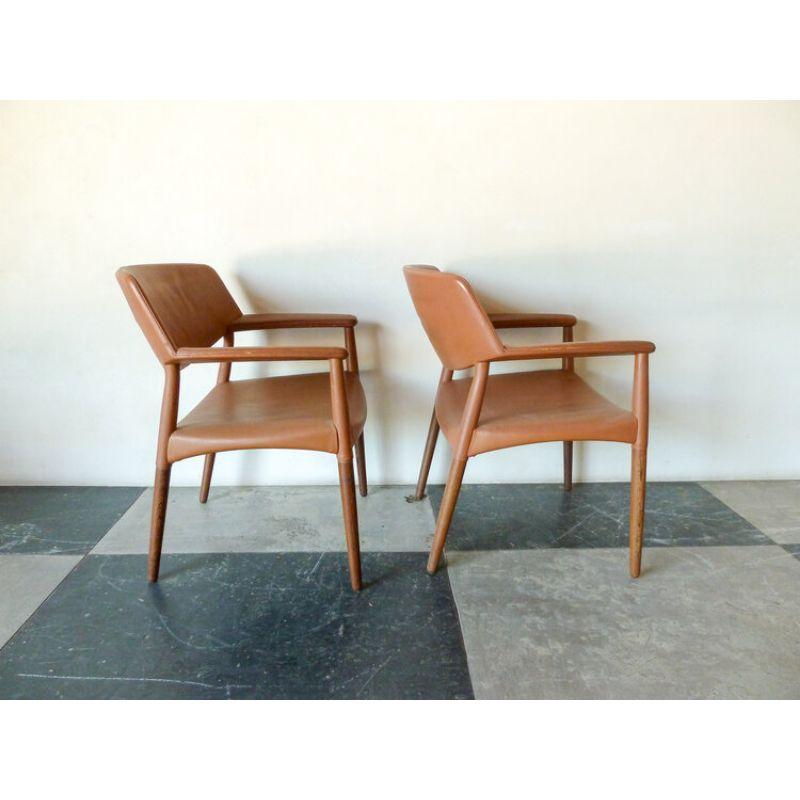 Pair of brown leather arm chairs by Ejner Larsen & Aksel Bender Madsen, Model 1924/S designed in 1954. The chairs include round wengé legs and painted brown leather upholstered on seat, back, and armrests. Made and marked with plaque by cabinetmaker