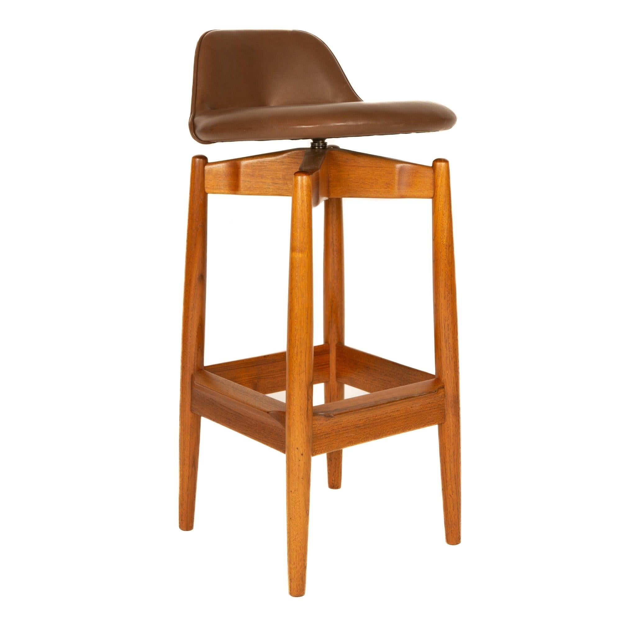 A teak barstool with a swiveling seat newly upholstered in brown leather.
