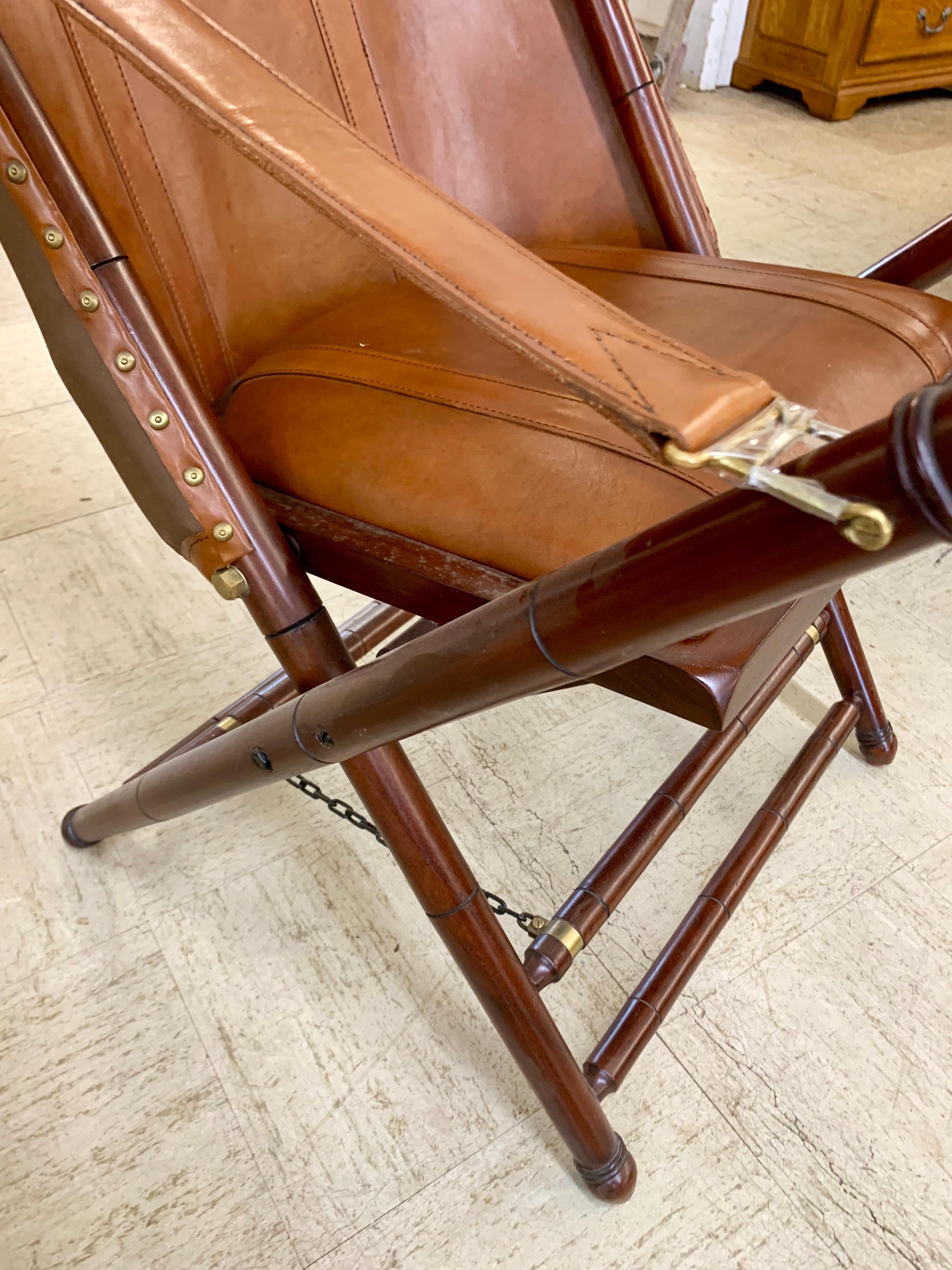 Rare Palecek brown leather campaign folding chair with matching ottomans/stool. Stool measures 22 inches wide x 21 inches deep x 16 inches high.
