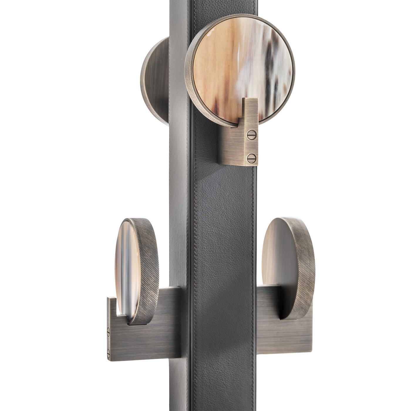 Functional yet sophisticated, this freestanding coat rack has a minimal design and refined details that will fit perfectly in a contemporary styled room. The wood structure, entirely upholstered with brown leather, is supported by a square base