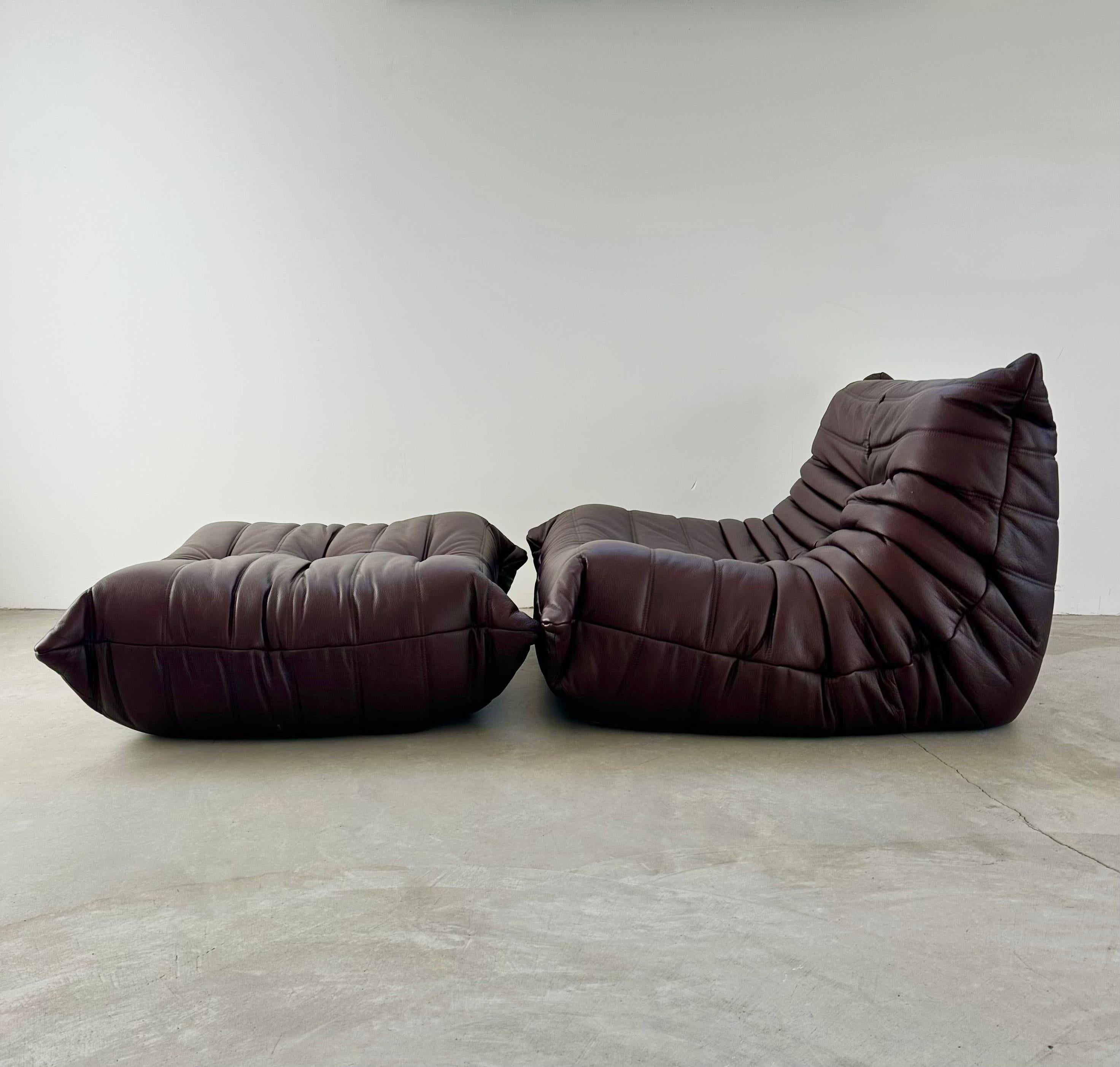 Classic French fireside Togo seat by Michel Ducaroy for luxury brand Ligne Roset. Originally designed in the 1970s the iconic togo sofa is now a design classic. This seat and ottoman pair comes in its original brown leather.

Timeless comfort and