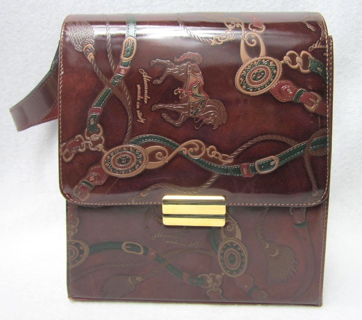 Stunning detailing on this Italian made handbag. Horse Motif. Luscious Brown Leather with Gold Tone Brass hardware and Footed. The Strap extends from 15 inches  long to 20 inches by opening the buckles on the side of the handbag. Measures- Wide 8