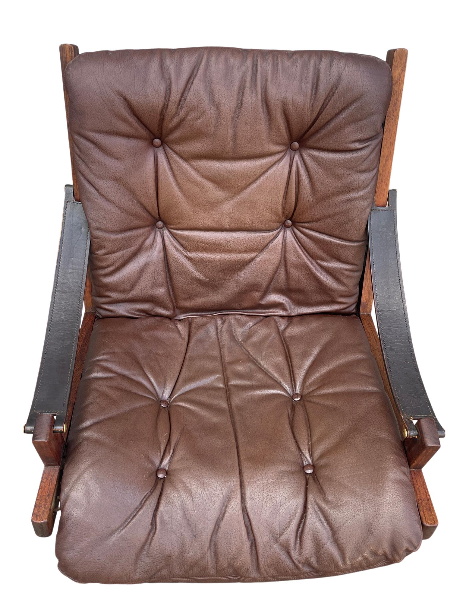 Brown leather “Hunter” Safari low lounge chair by Torbjørn Afdal for Bruksbo circa 1960. Solid rosewood frame with strung brown canvas back. Black belt leather arms with brass hardware. Soft dark brown leather seat cushions. All original beautiful