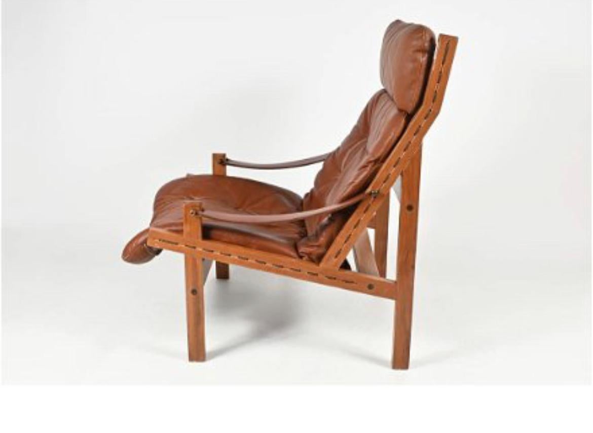 Brown leather “Hunter” Safari low lounge chair by Torbjørn Afdal for Bruksbo circa 1960. Solid rosewood frame with strung brown canvas back. Black belt leather arms with brass hardware. Soft dark brown leather seat cushions and headrest. All