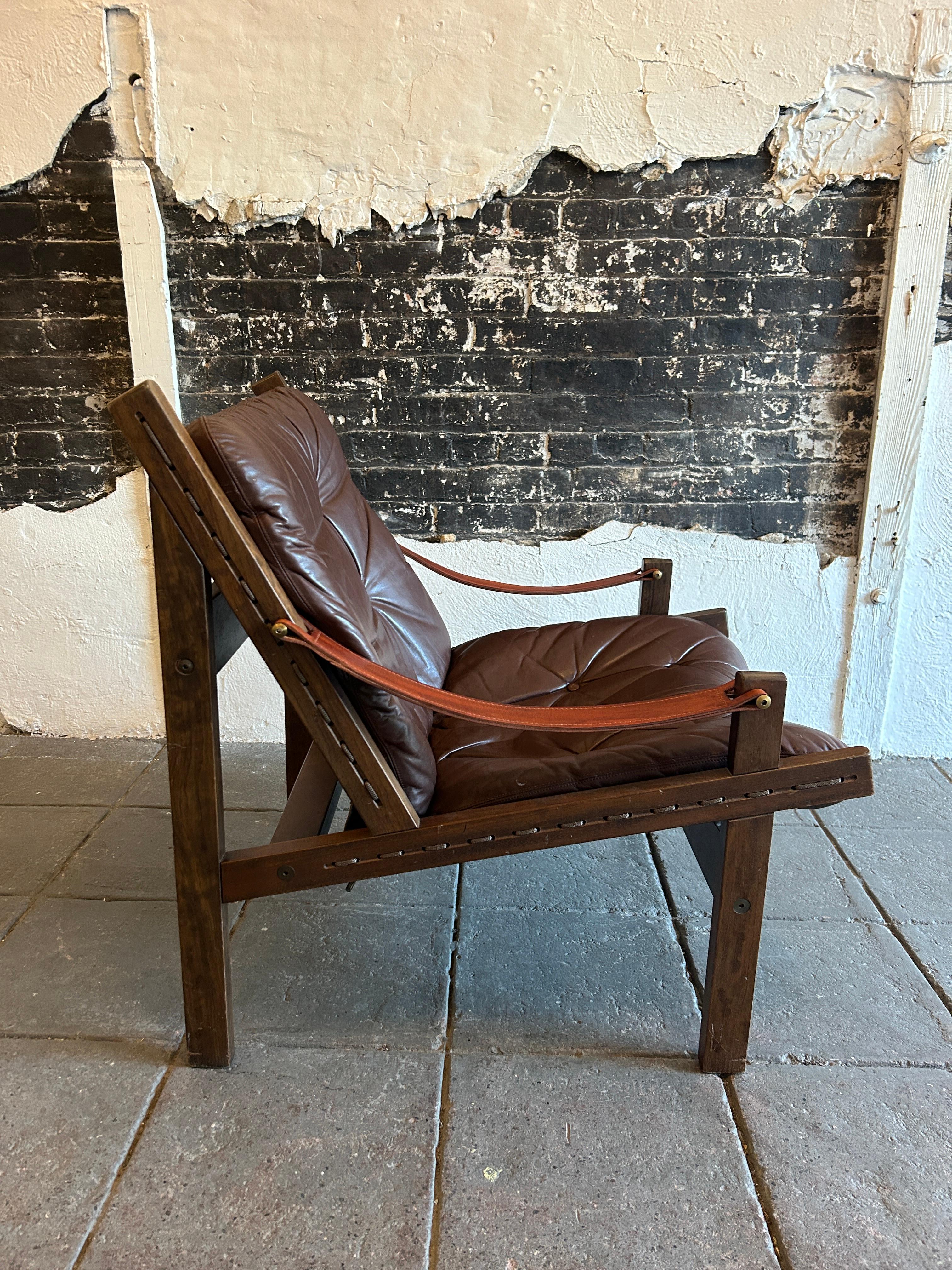 Brown leather “Hunter” Safari low lounge chair by Torbjørn Afdal for Bruksbo circa 1960. Solid rosewood frame with strung brown canvas back. brown belt leather arms with brass hardware. Soft dark brown leather seat cushions. All original beautiful