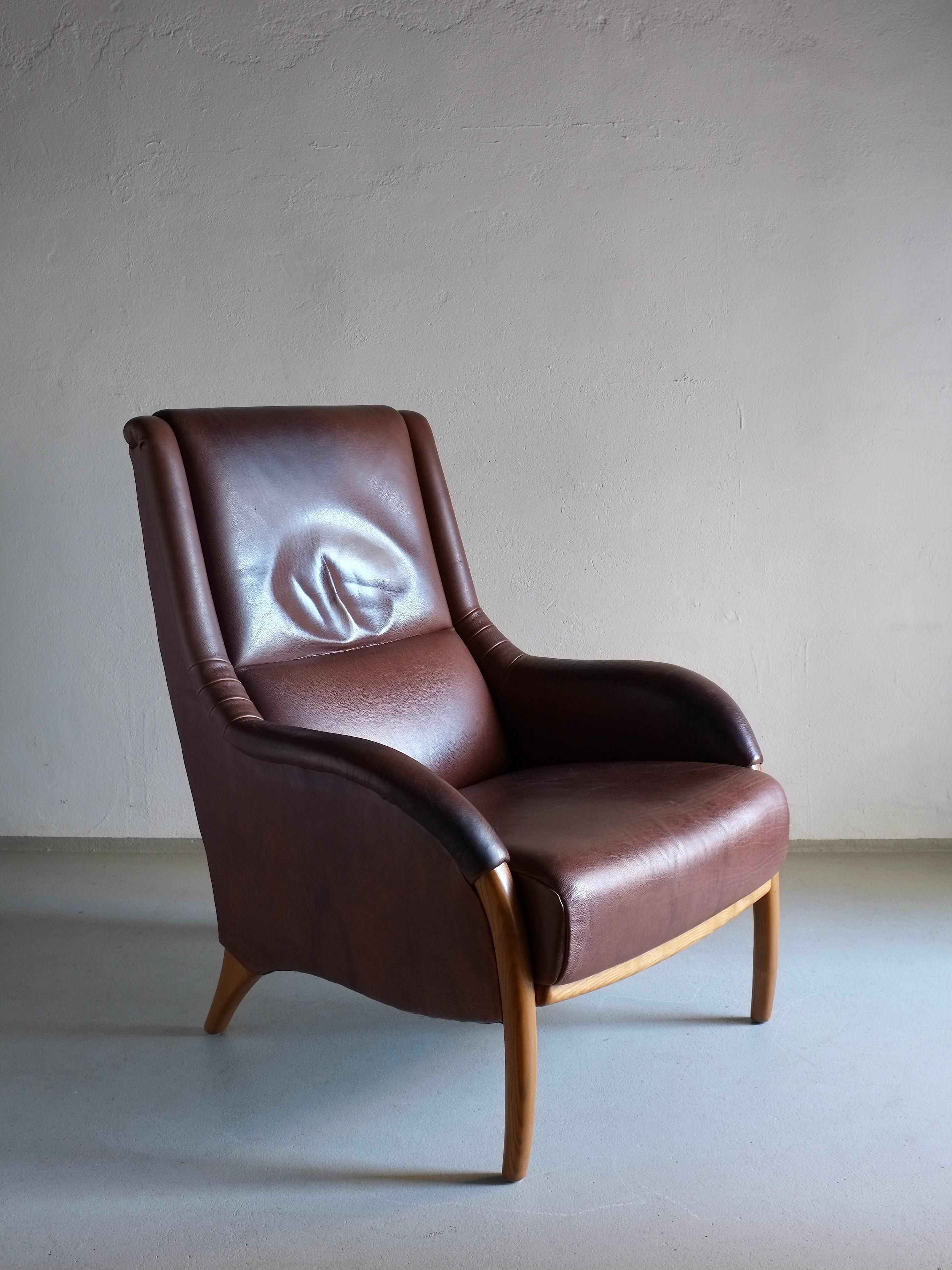 Sillón vintage de cuero marrón con detalles curvados. 