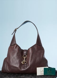 Brown leather monogram embossed bag with gold metal snap hook Gucci
