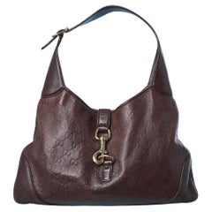 Brown leather monogram embossed bag with gold metal snap hook Gucci 