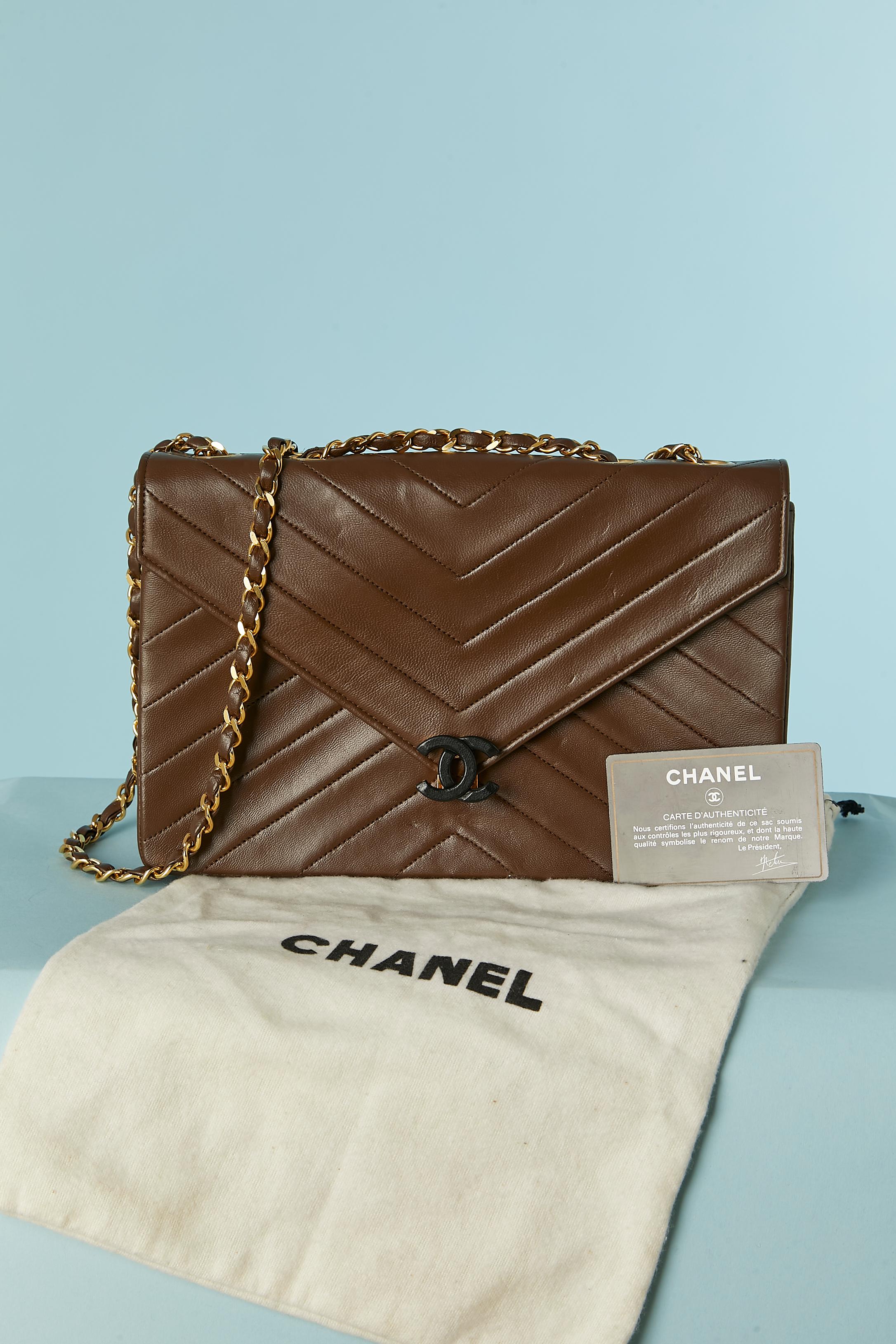 Brown leather shoulder bag with top-stitching and chain. 
Black leather lining. One flat pocket with zip inside and one flat pocket without zip. 