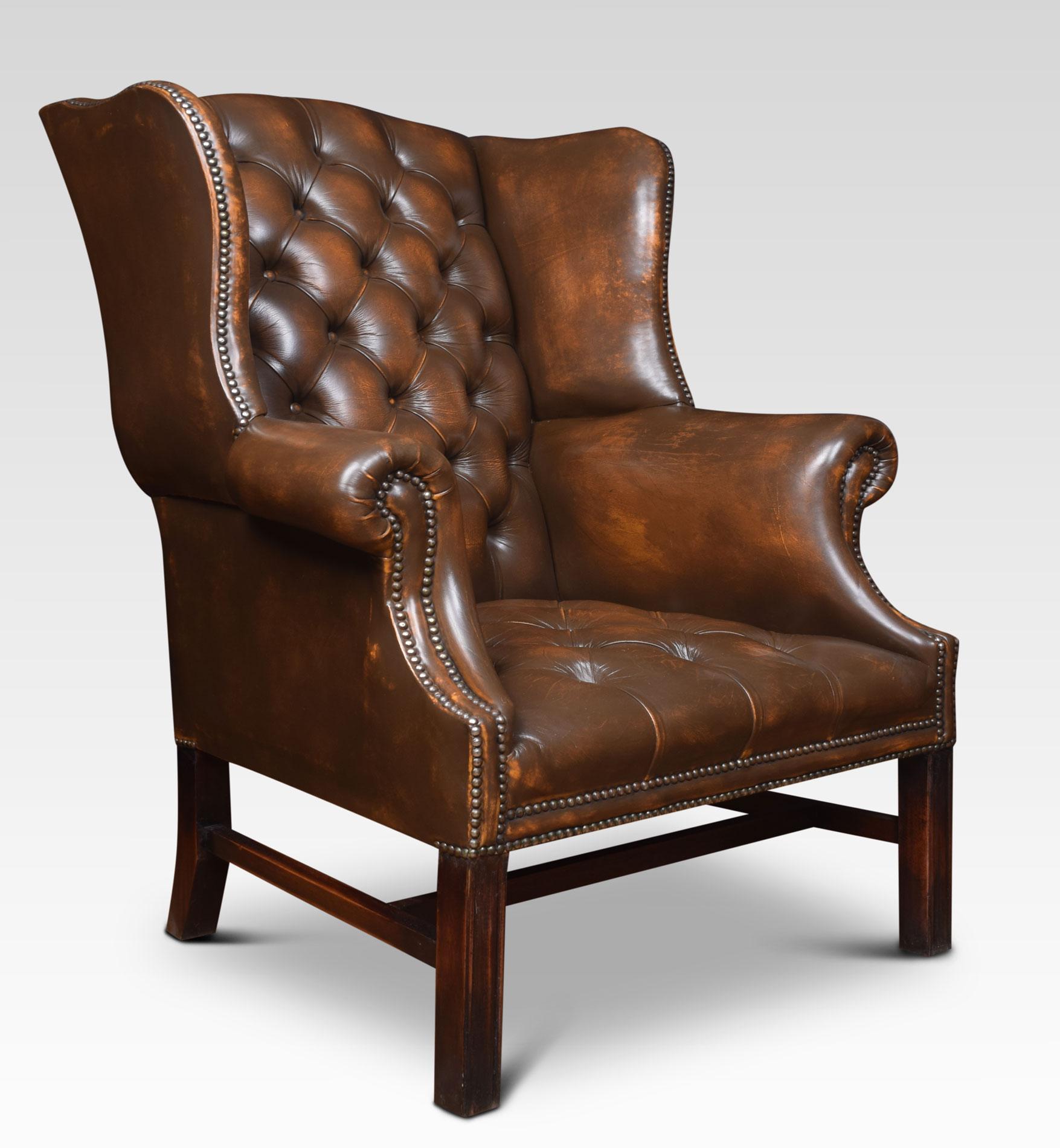 Mahogany framed wing armchair of generous proportions, the arched top above deep buttoned back, upholstered arms and seat in brown leather, raised up on square supports united by H stretcher.
Dimensions:
Height 42.5 inches height to seat 17