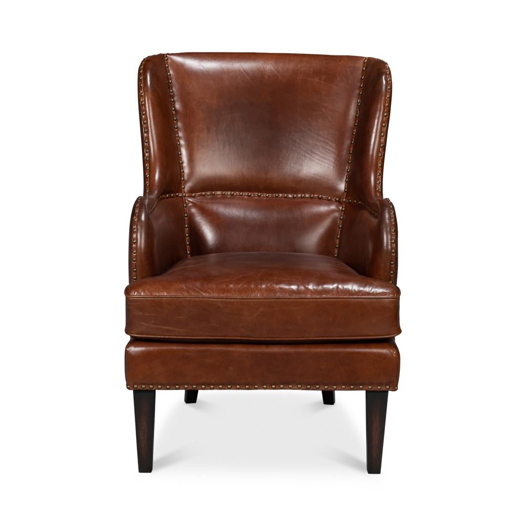 Upholstered in rich, full-grain Newark brown leather, this chair exudes timeless sophistication. The classic wingback design features curved arms, and stitched panel detailing with meticulous nailhead trim, enhancing its refined look.

Supported by