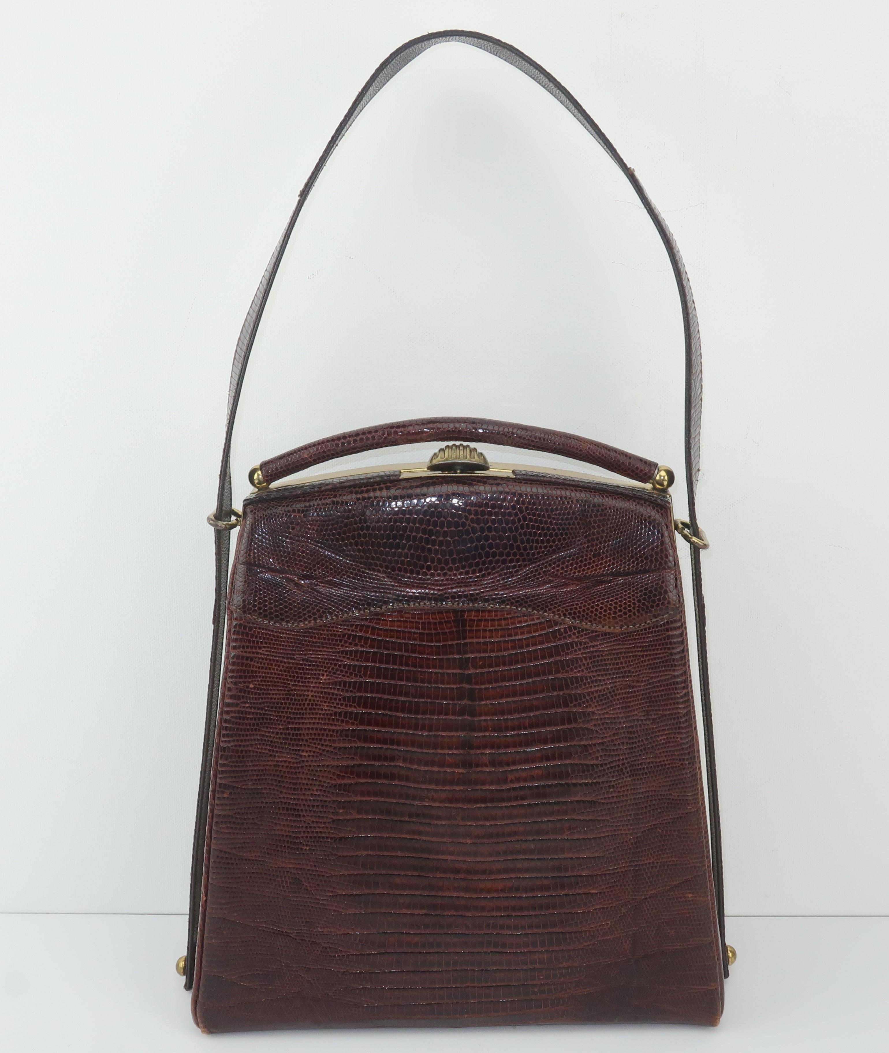 A 1950's brown lizard skin handbag with a unique tall silhouette accented by a skin covered arched bar at the top of the frame.  The handle feeds through glides at the top of the frame and is tacked at the base adding another interesting design