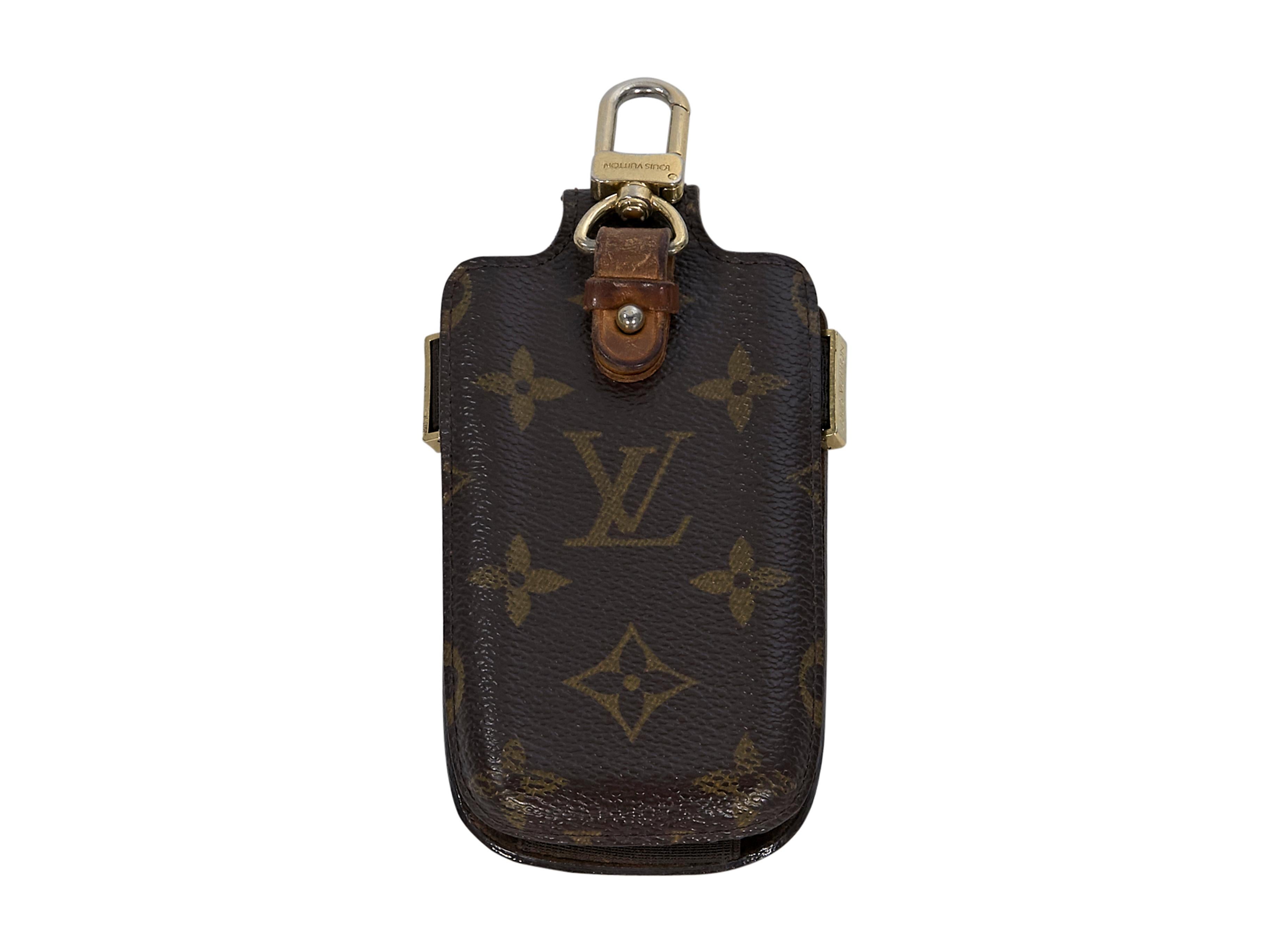 Product details:  Brown logo embossed leather phone case by Louis Vuitton.  Gold-tone keychain ring at top. Snap clip at back. Velcrow closure strap.  2.75