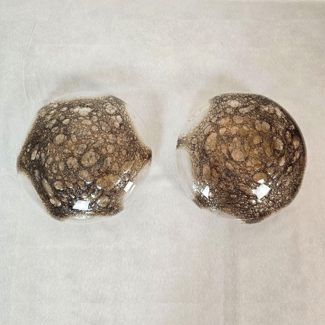 Pareja de apliques redondos Mid Century Modern atribuidos a Carlo Nason para Mazzega  Italia años 60. 
Los apliques de pared Mid Century Modern están hechos de un globo transparente de cristal de Murano con una decoración irregular marrón,
dentro de