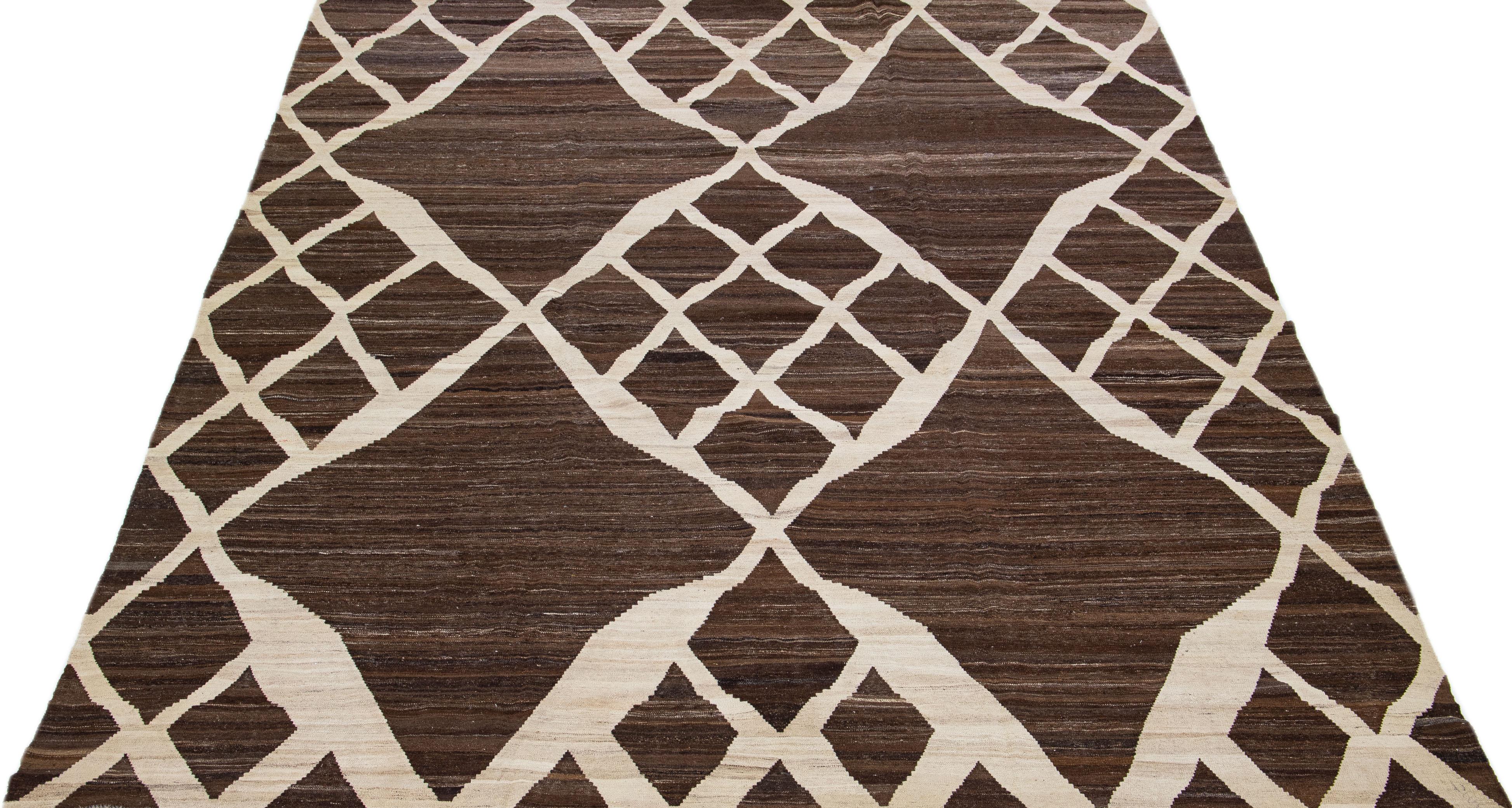 Magnifique tapis Kilim contemporain en laine tissée à plat avec un champ de couleur marron. Ce tapis turc présente un magnifique motif géométrique en beige. 

Ce tapis mesure : 10'1