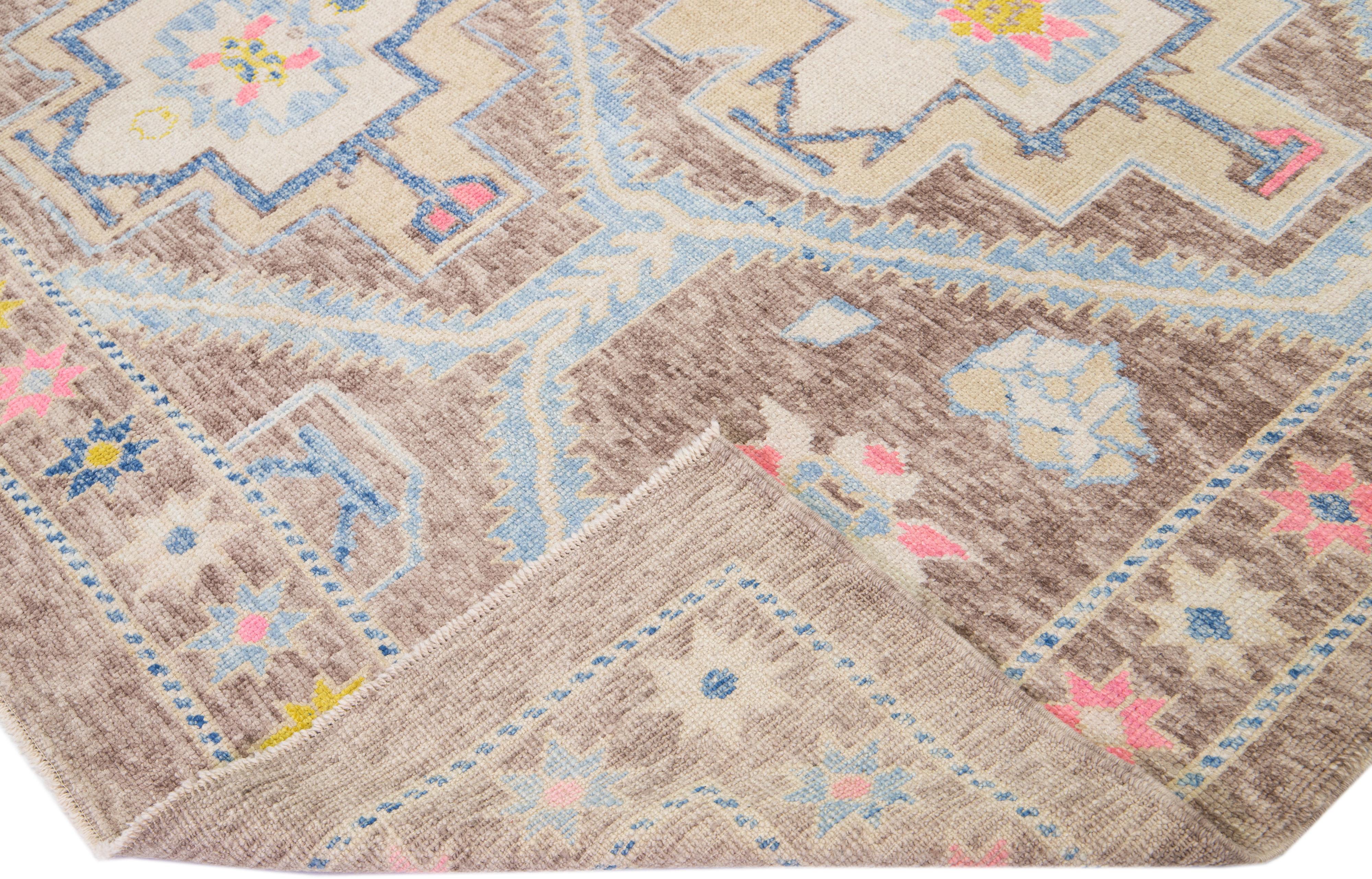 Beautiful modern Turkish hand-knotted wool rug with a brown color field and blue, pink, and beige accents in a gorgeous all-over geometric floral design.

This rug measures: 9'4