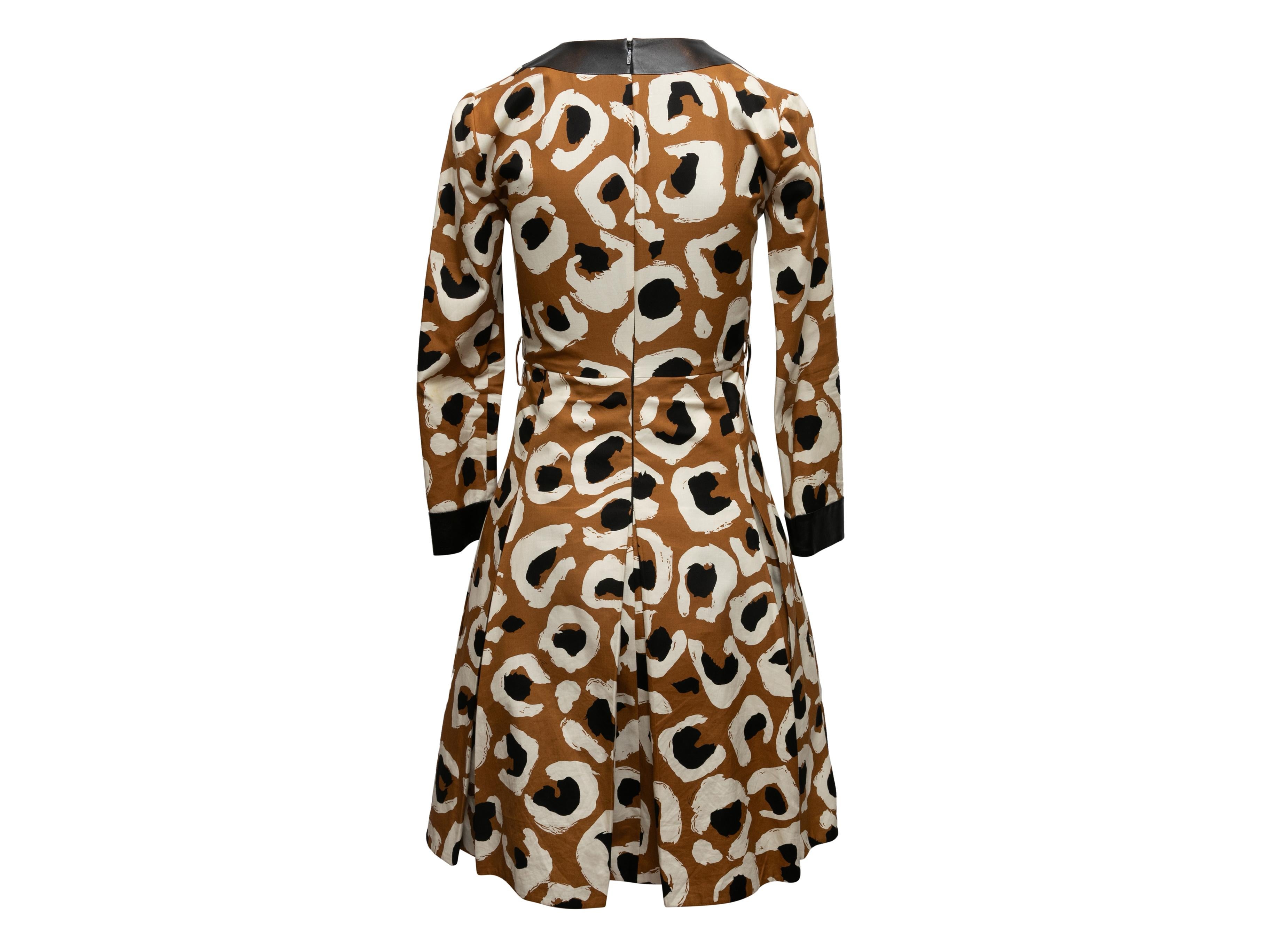 Brown, cream, and black abstract print long sleeve dress by Gucci. Leather trim throughout. V-neck. Pleated skirt. Zip closure at center back. Designer size 38. 30