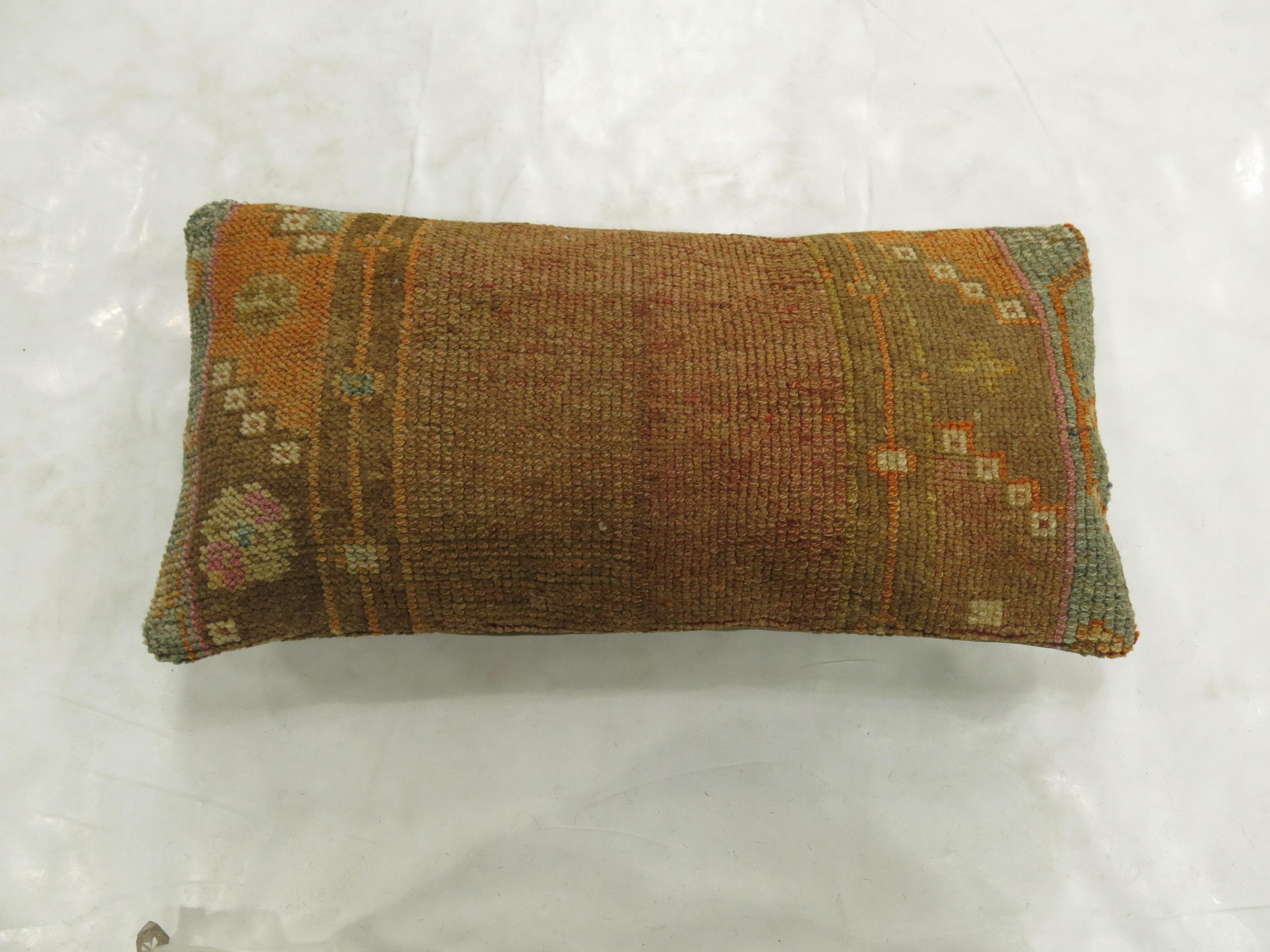 Bolster size pillow made from a vintage Turkish Anatolian rug. Brown, orange, soft green, lavender accents

Measures: 11'' x 24''.