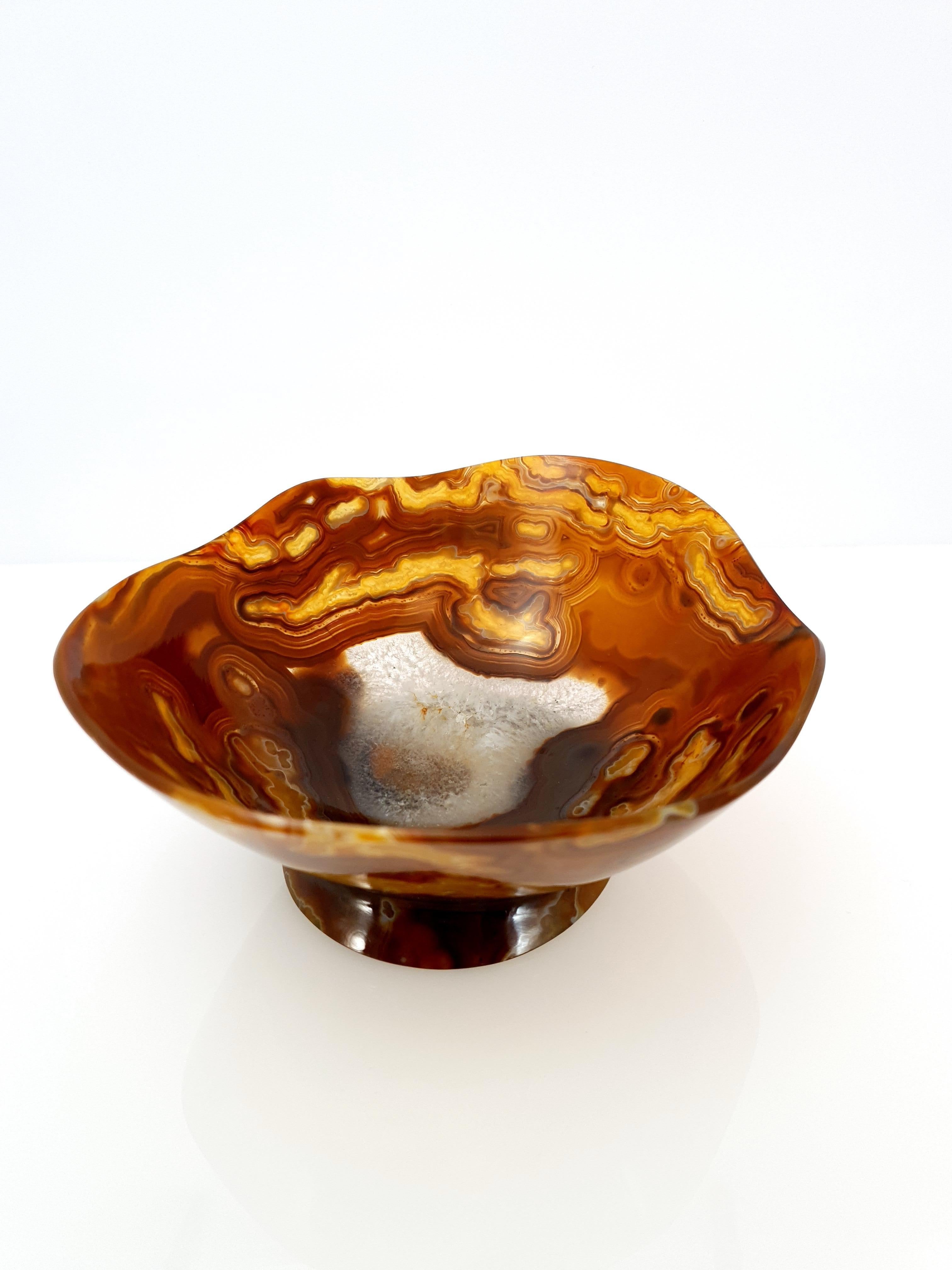 A natural handmade orange brown banded Agate Bowl with a crystalized center.
The bowl is cut so thin that the material is translucent. 

It's a great piece for decoration on a desk, vanity, or even as a special gift.
