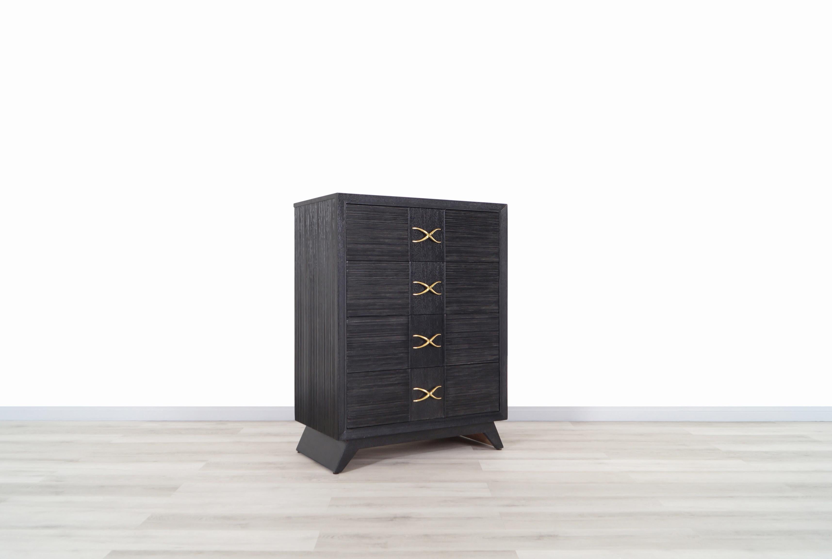 Vintage chest of drawers / tall dresser designed by Paul Frankl for Brown Saltman, circa 1950s. This beautiful chest of drawers features four large pull-out dovetailed drawers, all integrated with original brass X-pulls. Its spacious drawers make it