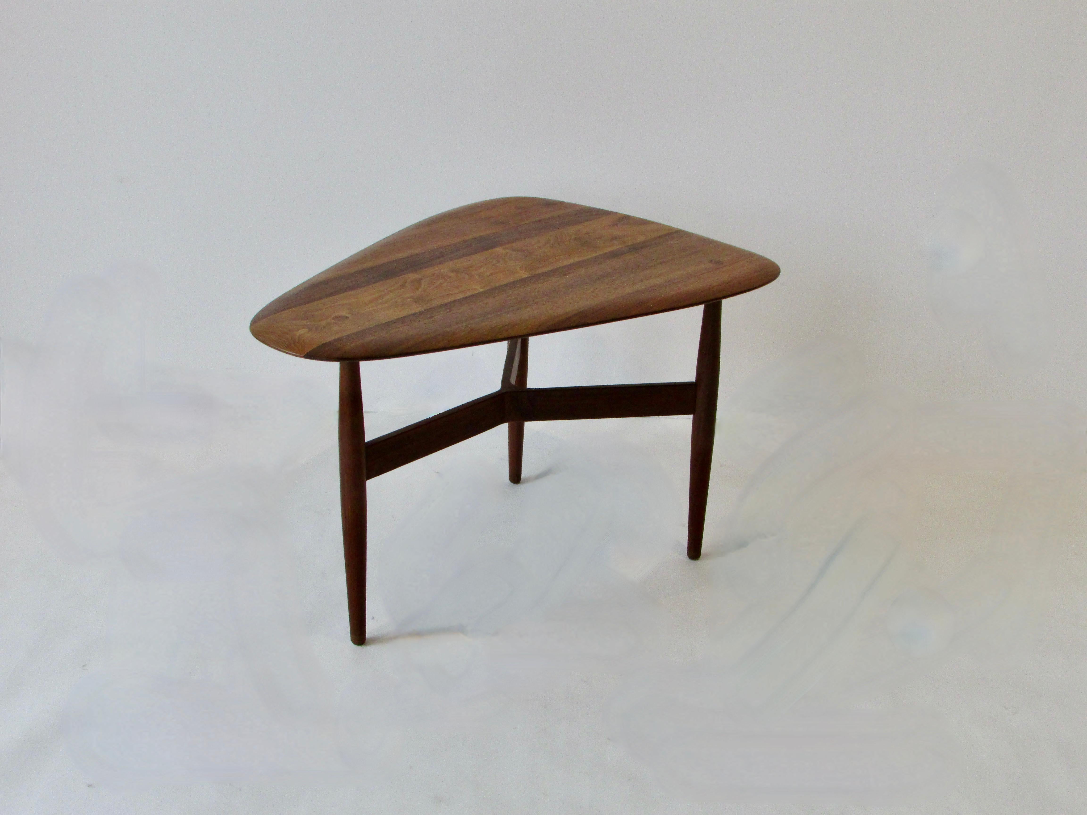 Side table by Brown Saltman. Wood stretcher runs between three legs which tenon through the guitar pick shaped top.