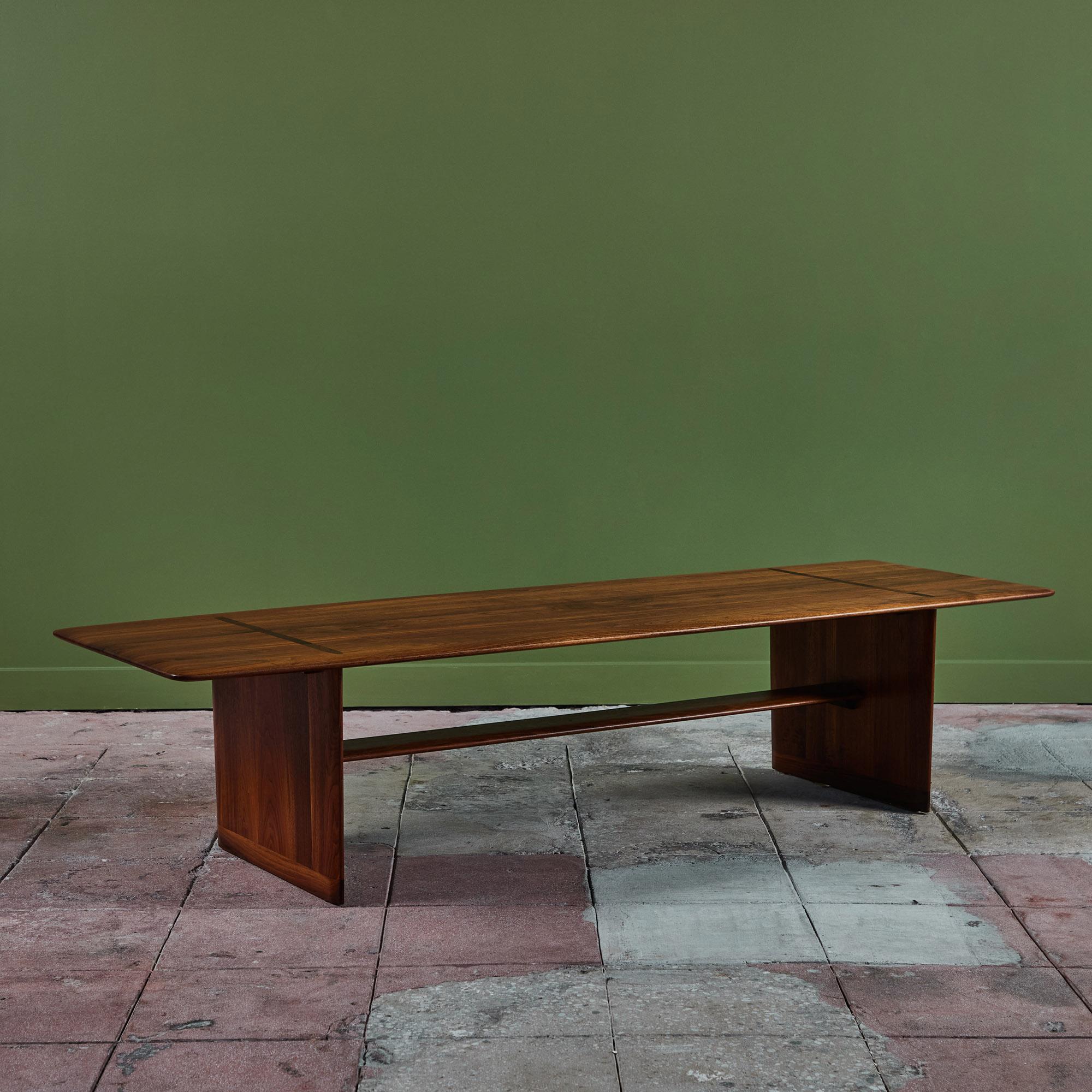 Brown Saltman rectangular coffee table, c.1950s, USA. The table features a knife edge walnut table top with beautiful exposed joinery work where the legs meet the top. The legs are connected by one long stretcher.

Dimensions
65.5” width x 21.25