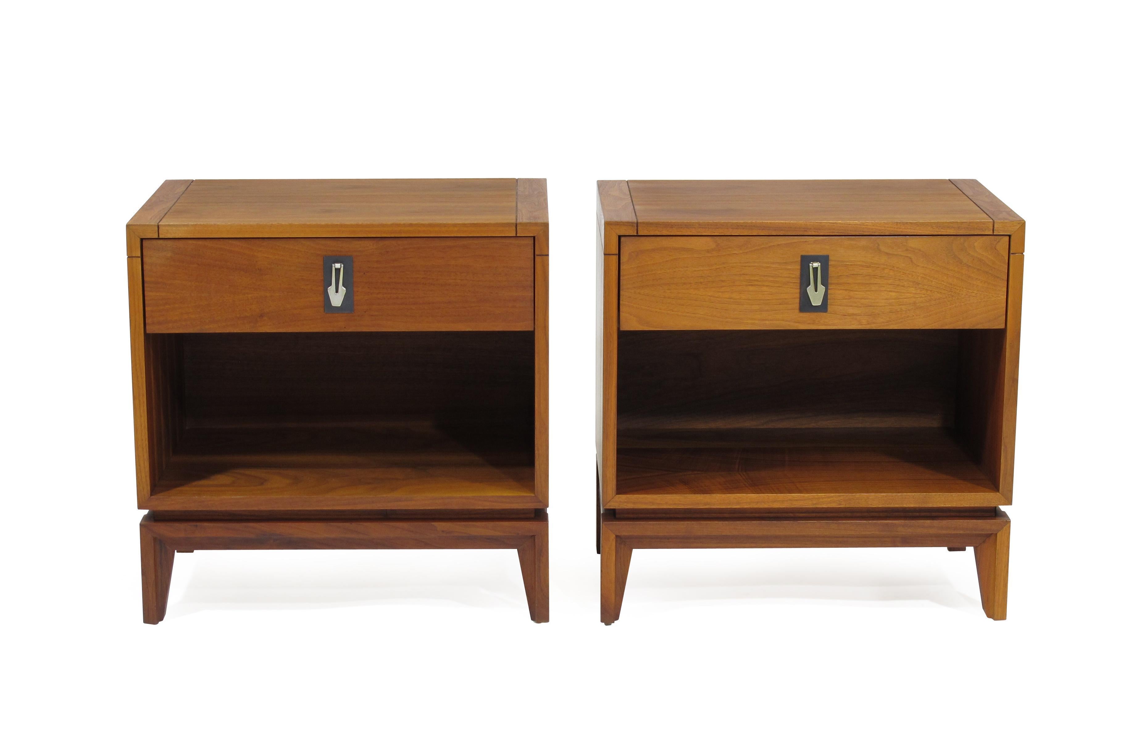 Midcentury walnut nightstands by Brown Saltman. One-drawer with metal drop-pull over an open space for storage, raised on tapered legs.