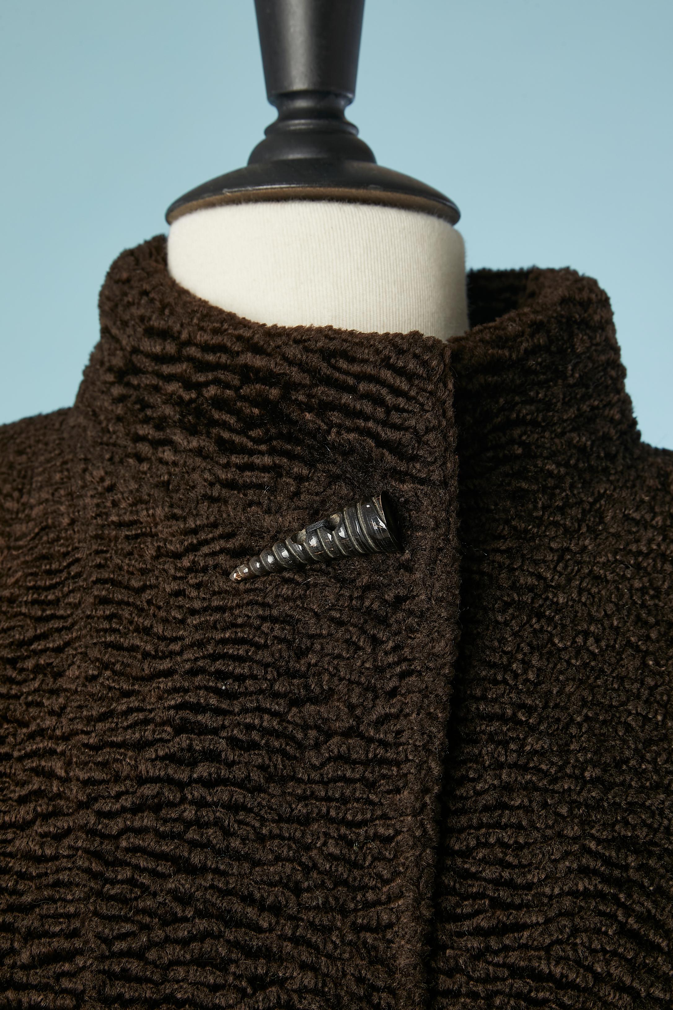 Manteau court marron à boutonnage unique en faux astrakan . Composition du tissu principal : 55% rayonne, 45% coton. Doublure en acétate. 
Des pads d'épaule. Un bouton en forme de coquille sur le  en haut, au milieu, à l'avant.
Poches sur les deux
