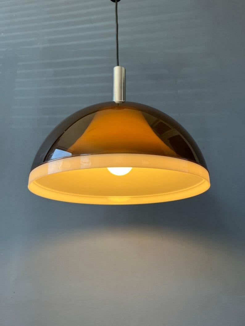 Very rare space age pendant lamp by Dijkstra with a double smoked acrylic glass shade. The outer shade is transparent and has a dark, copper-like colour, the inner shade is white. Together they create an astonishing light effect. The lamp requires