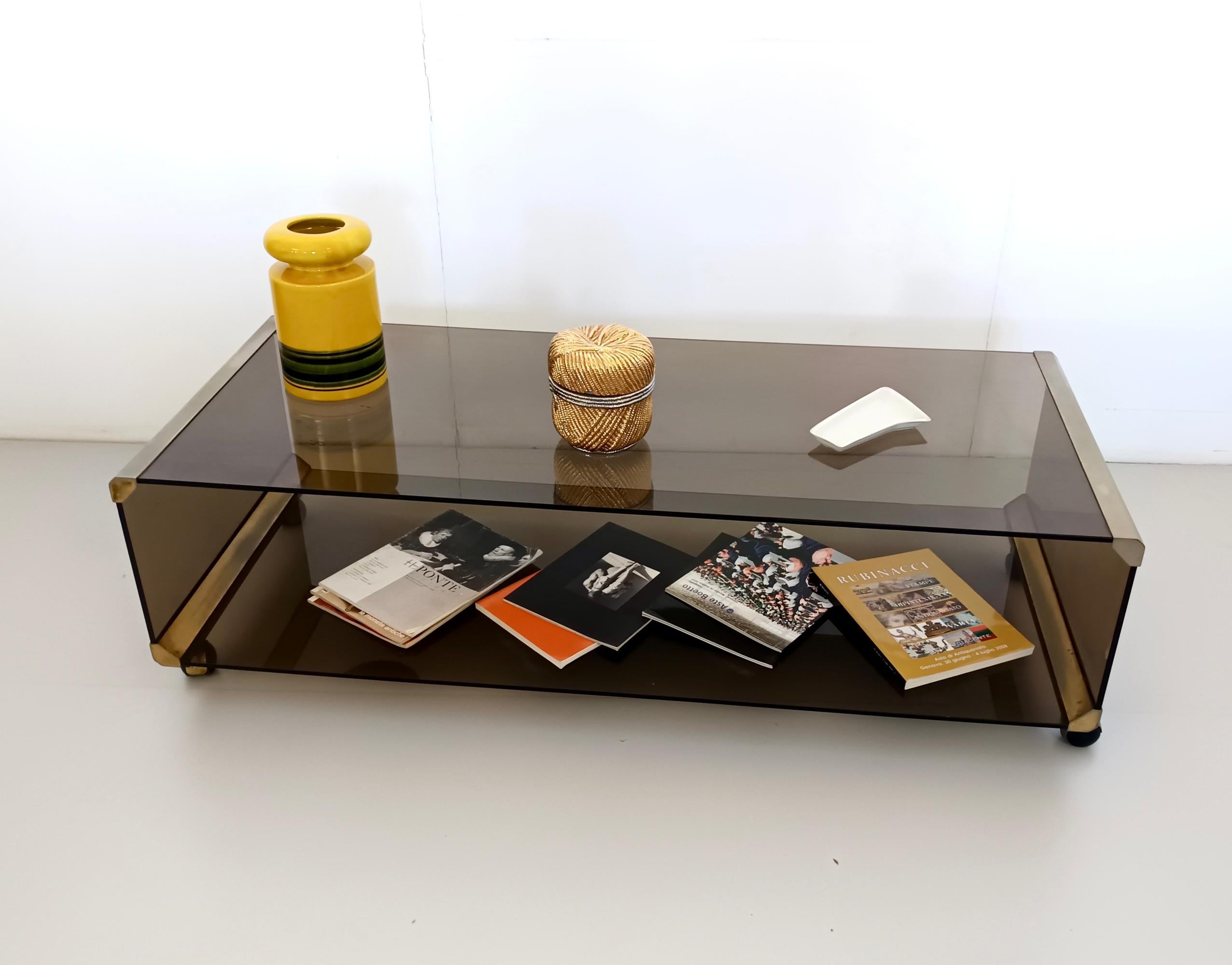 Made in Italy, 1970s. 
It is made in brown smoked tempered glass. This coffee table /TV stand features casters and anodized aluminum parts.
It is a vintage piece, therefore it might show slight traces of use such as an imperceptible chip on the