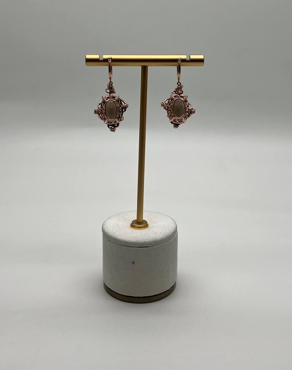 Questi orecchini presentano un quarzo fumé marrone scuro e sfaccettato, incastonato in un'intricata lavorazione del metallo. Il design è caratterizzato da punte delicate e dettagli ornamentali che creano un contrasto sorprendente con la tonalità