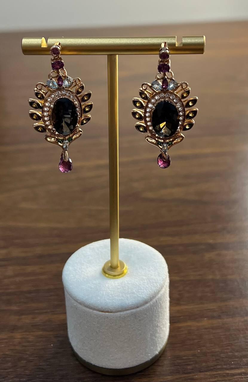 Elegant drop earrings with a striking design.

These sophisticated earrings are crafted with meticulous attention to detail.

Each earring features a brown smoky quartz, encircled by a halo of sparkling diamonds and other semi-precious