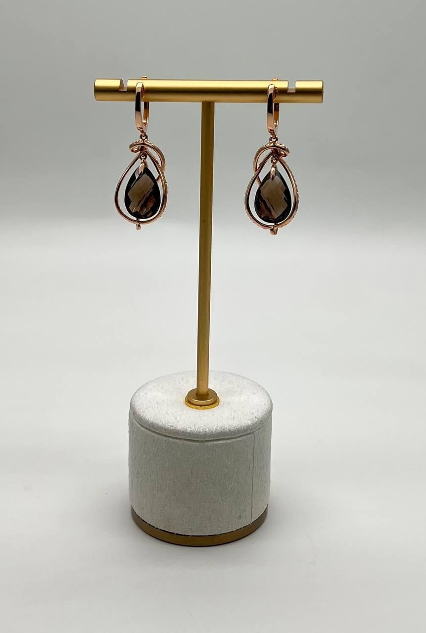 Questi sofisticati orecchini sono realizzati con precisione e maestria.
Ogni orecchino presenta un design a goccia, ornato da un quarzo fumé marrone centrale.
La gemma è racchiusa in una delicata e scintillante cornice di diamanti più piccoli, che