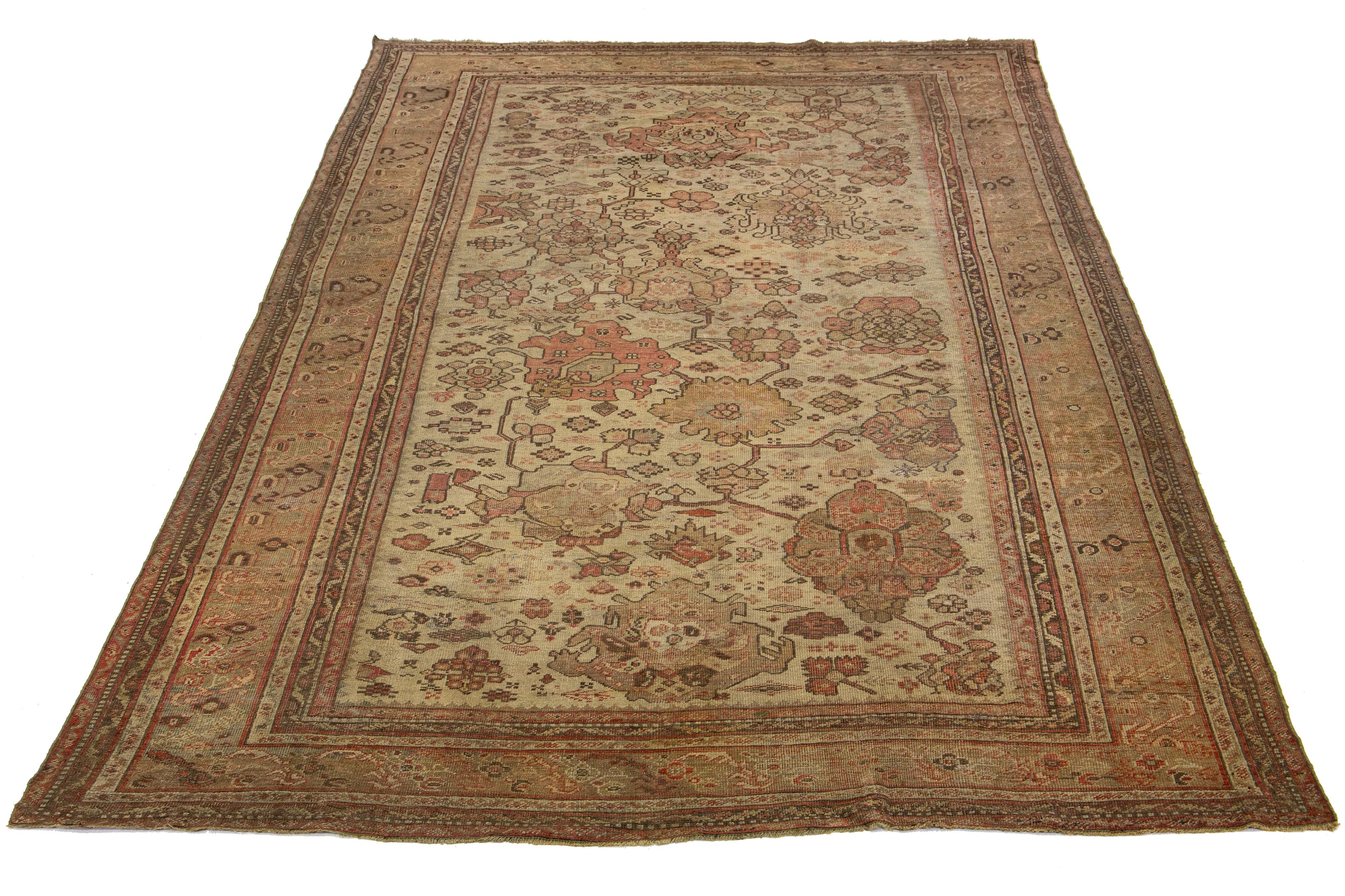 This antique Turkish wool rug from the 19th century features a charming terracotta-colored base and is meticulously hand-knotted with great attention to detail. It showcases stunning tan-golden accents that display a captivating floral