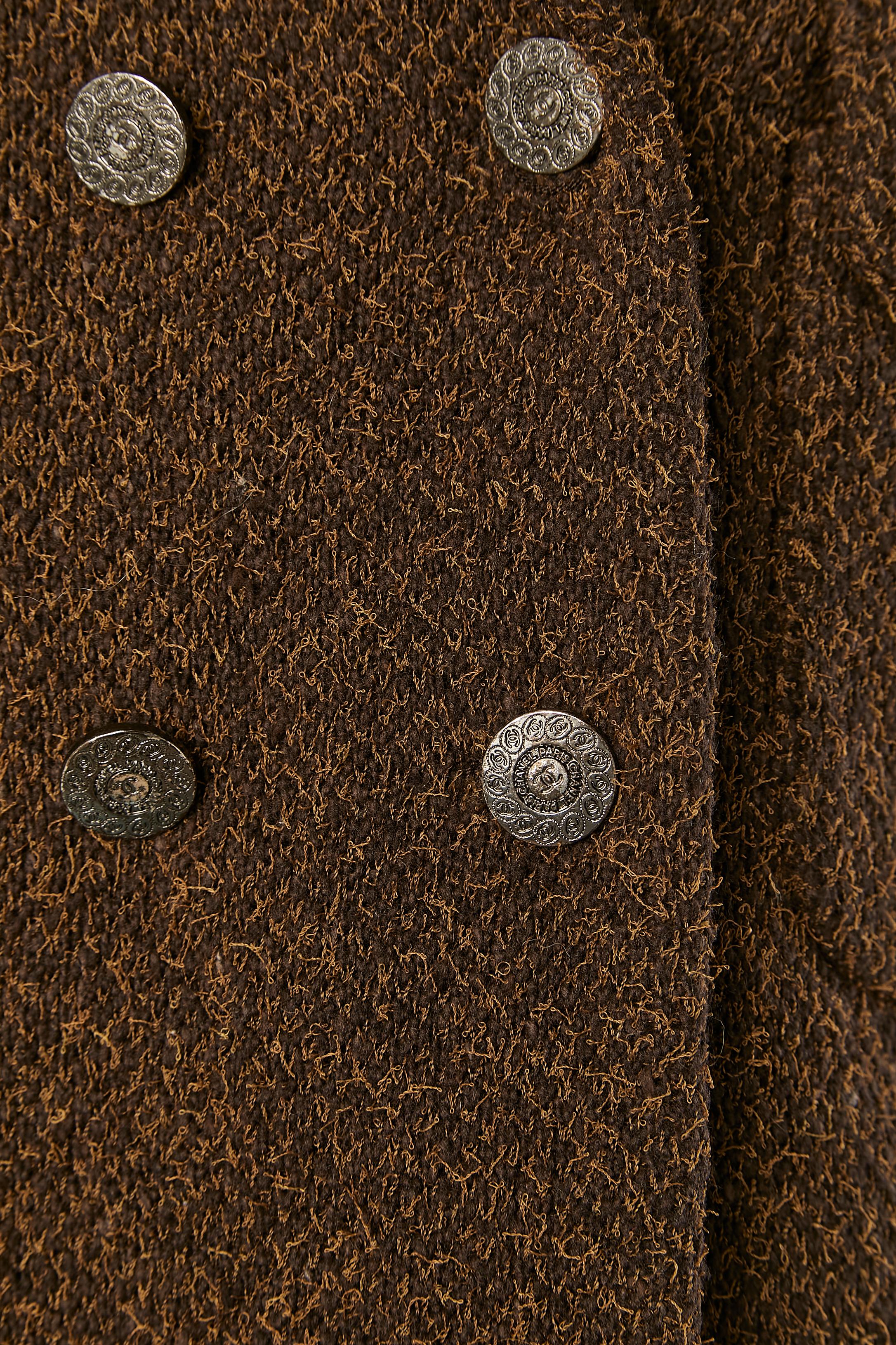Veste en tweed marron à double boutonnage. Composition du tissu principal : 50% nylon, 37% laine, 13% angora. Doublure en soie. 
Chaîne sur le bord inférieur intérieur. Bouton et boutonnière marqués sur le devant, sur la poche  et sur les poignets.