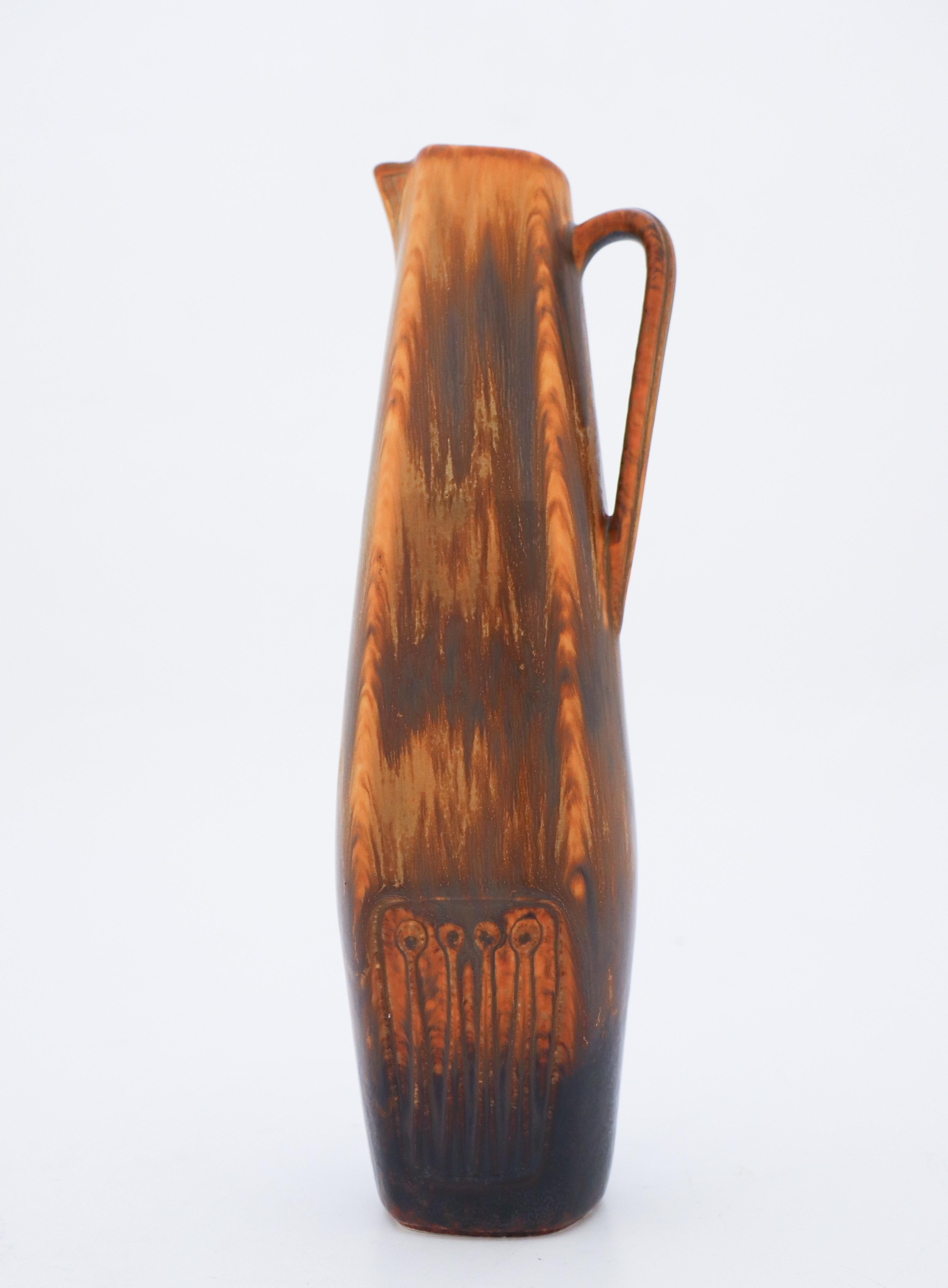 Die braune Vase wurde von Gunnar Nylund bei Rörstrand entworfen und ist 26,5 cm (10,6) hoch. Es ist in nahezu neuwertigem Zustand und als 1:st-Qualität gekennzeichnet. 

Gunnar Nylund wurde 1904 in Paris geboren. Seine Eltern arbeiteten als
