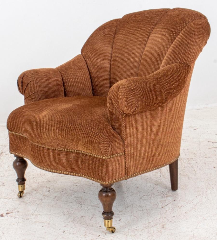Brown and vermilion chenille upholstered arm chair, in the Victorian taste, with rounded channel-upholstered back and scrolling arms above a shaped seat on turned front legs with casters,and splayed back feet. 

Dimensions: 31
