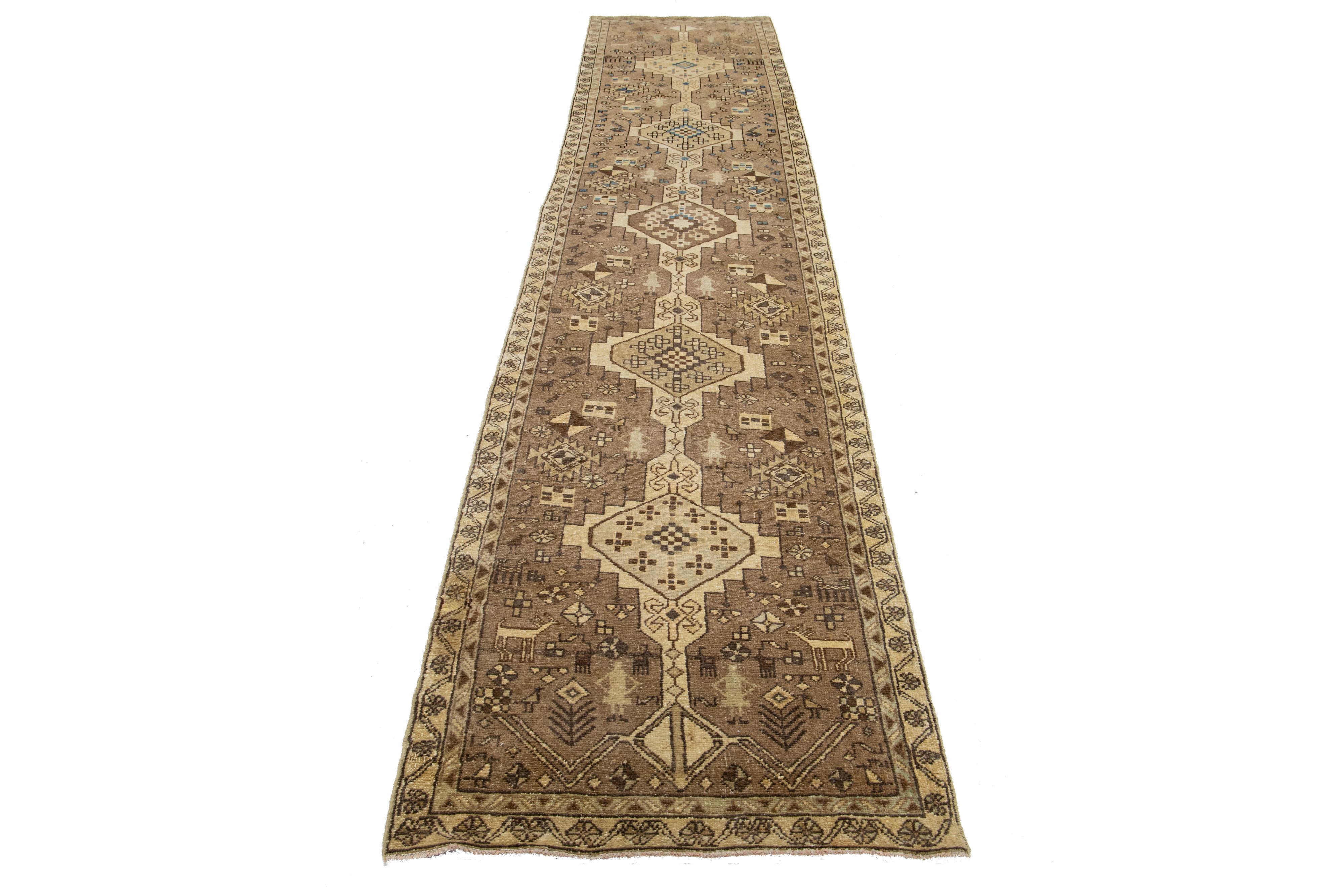 Ce chemin de table en laine vintage présente un champ marron avec des accents tribaux beiges et bleus d'origine persane.

Ce tapis mesure 2'11