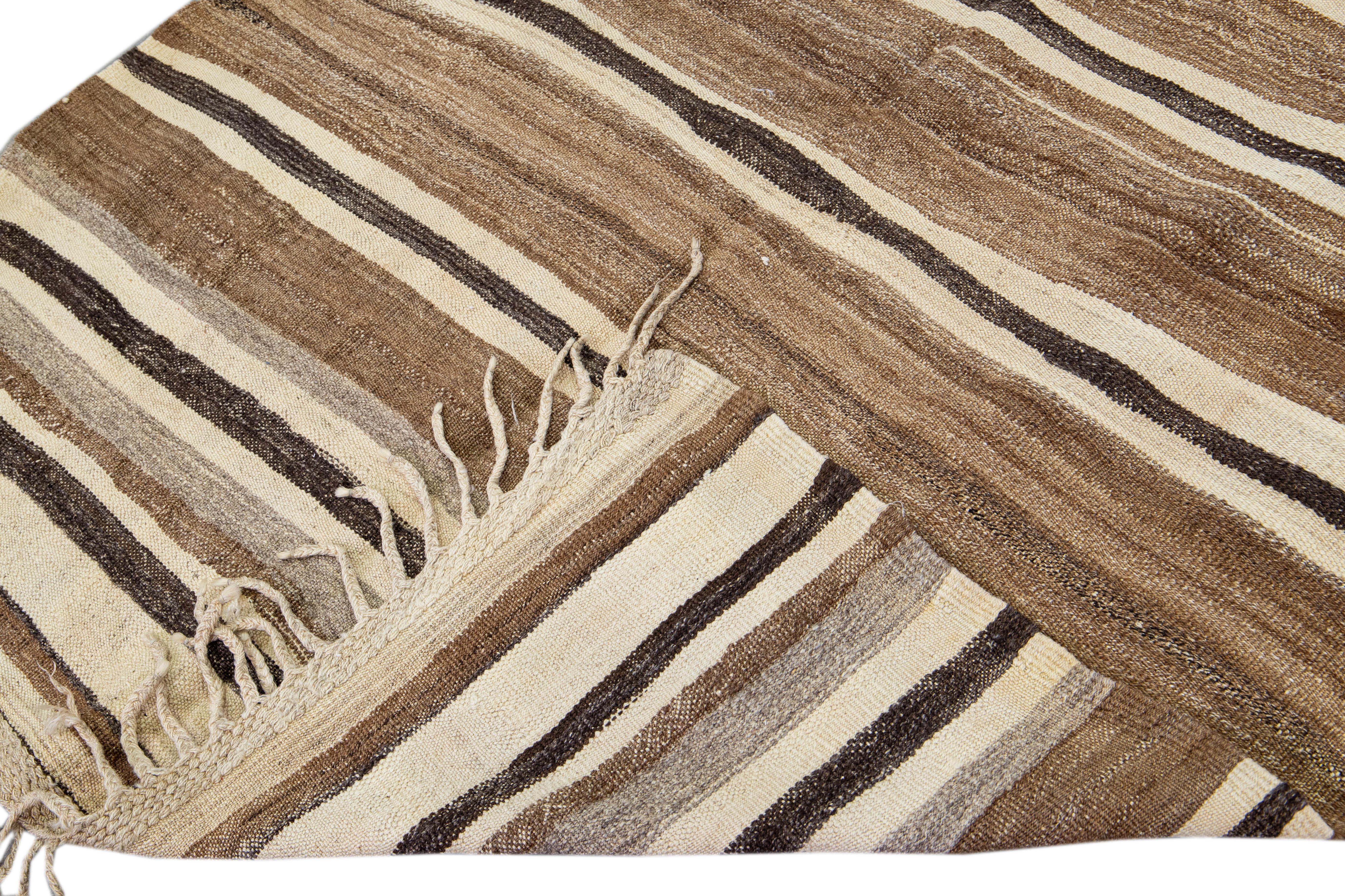 Beautiful kilim handmade wool rug with a brown field. This Vintage flatweave rug has beige Striped accents features a gorgeous all-over design with beige fringes.

This rug measures: 4'8