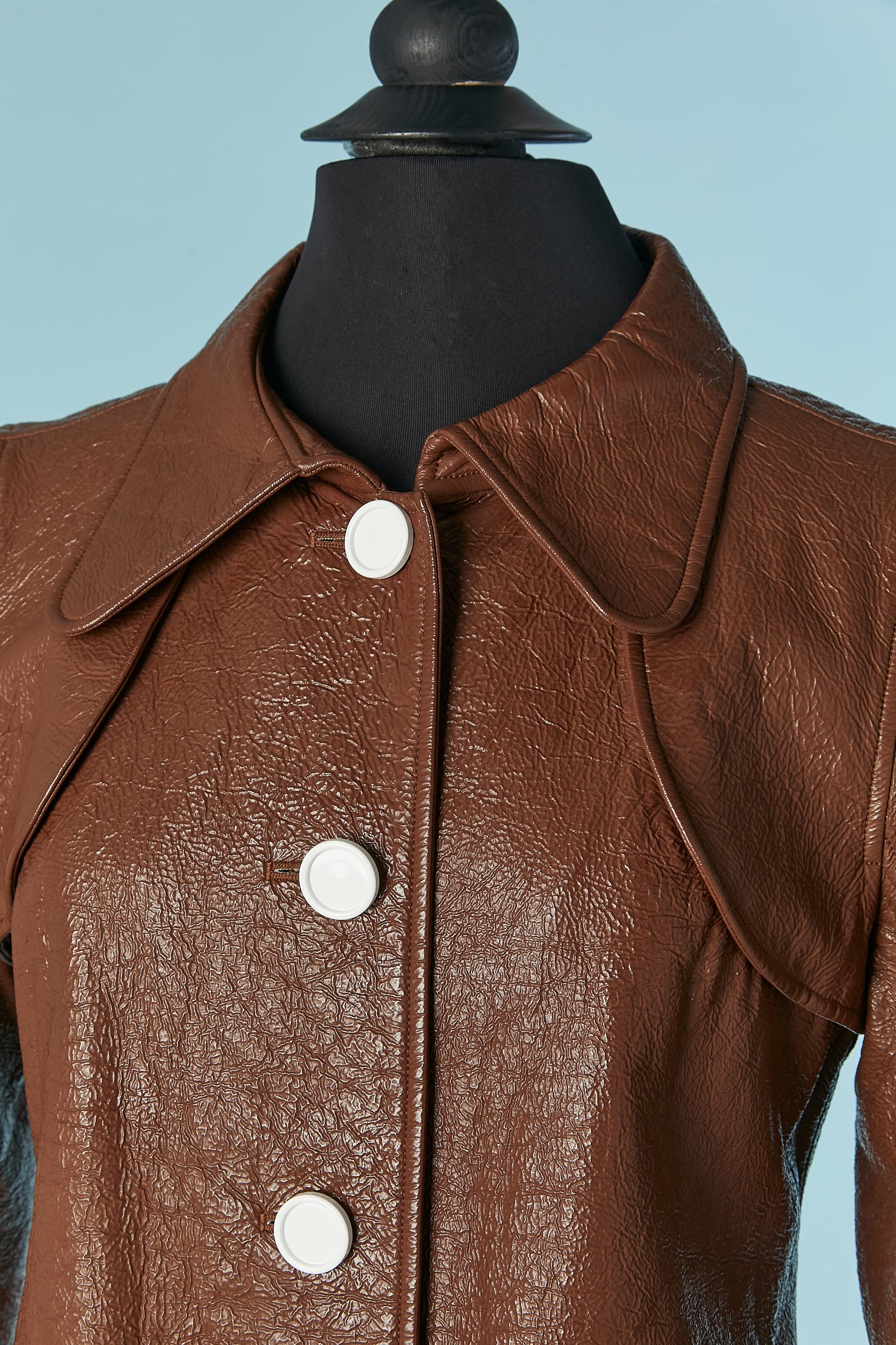 Manteau à simple boutonnage en vinyle marron avec fermeture à boutons blancs sur le milieu du devant et sur les poches. Composition du tissu principal : 80% coton, 20% polyuréthane.
Composition de la doublure marquée : 55% acétate, 45% cupro.