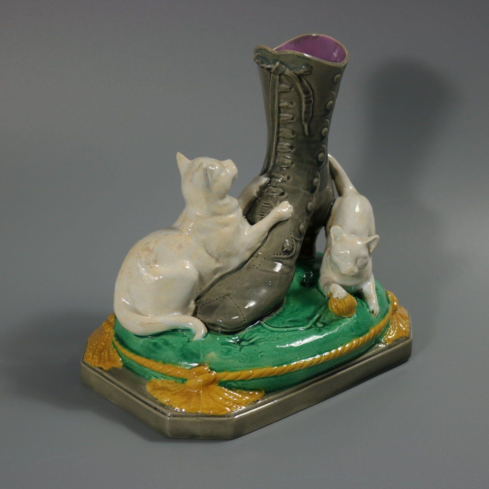 A.A. Brown Moore & Co. Vaso in maiolica con due gatti o gattini che giocano con una palla, intorno a uno stivale appoggiato su una base a cuscino con nappe. Colorazione: predominano il bianco, il verde e il grigio. Riporta un numero di modello, 'B'.