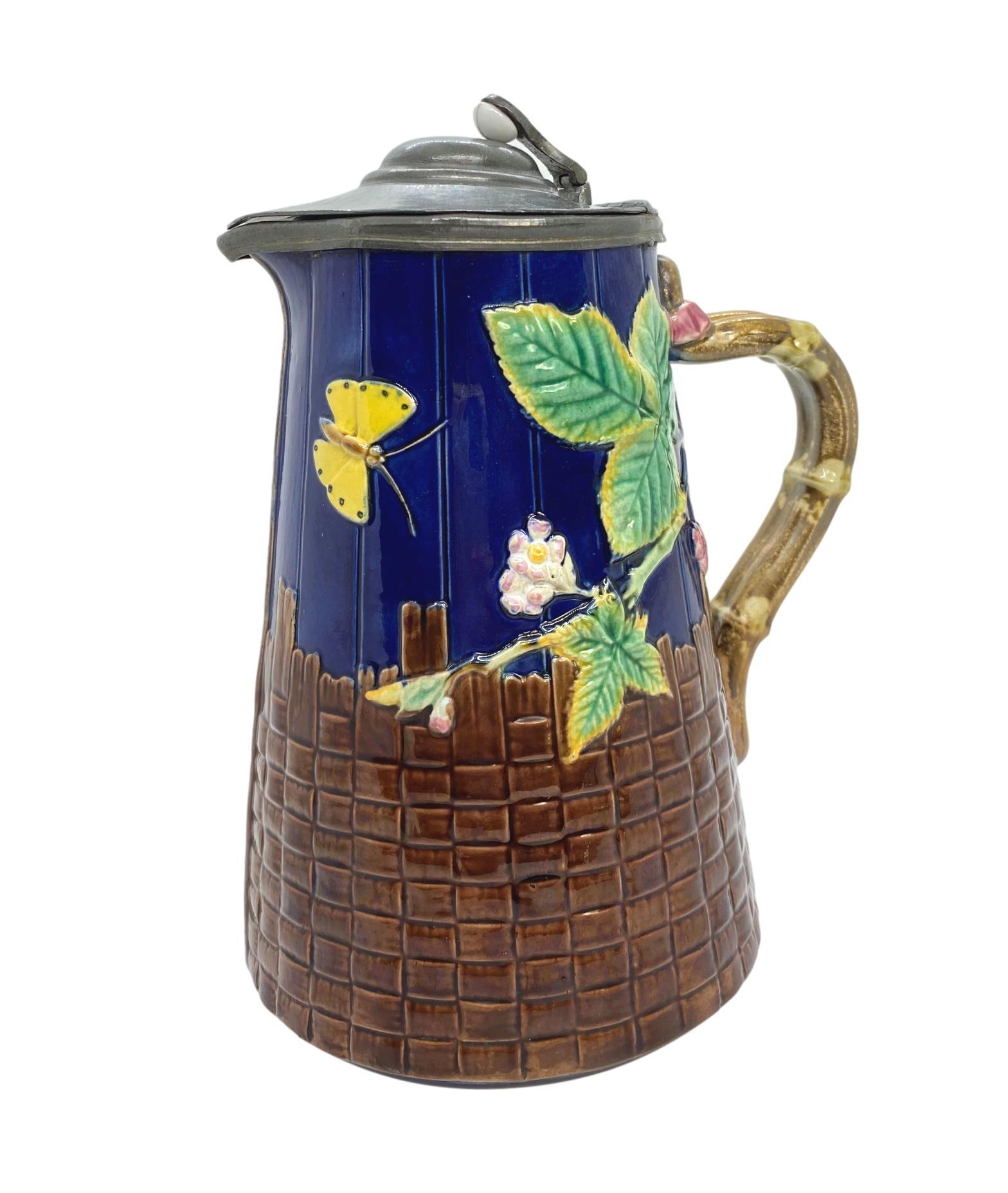 T. C. Brown-Westhead Moore & Co. Majolica Butterfly Pitcher, on cobalt blue-glazed simulated wooden staves and brown basketweave, with faux bamboo handles, the interior glazed in lavender, the reverse with British Registry Mark for 19 September
