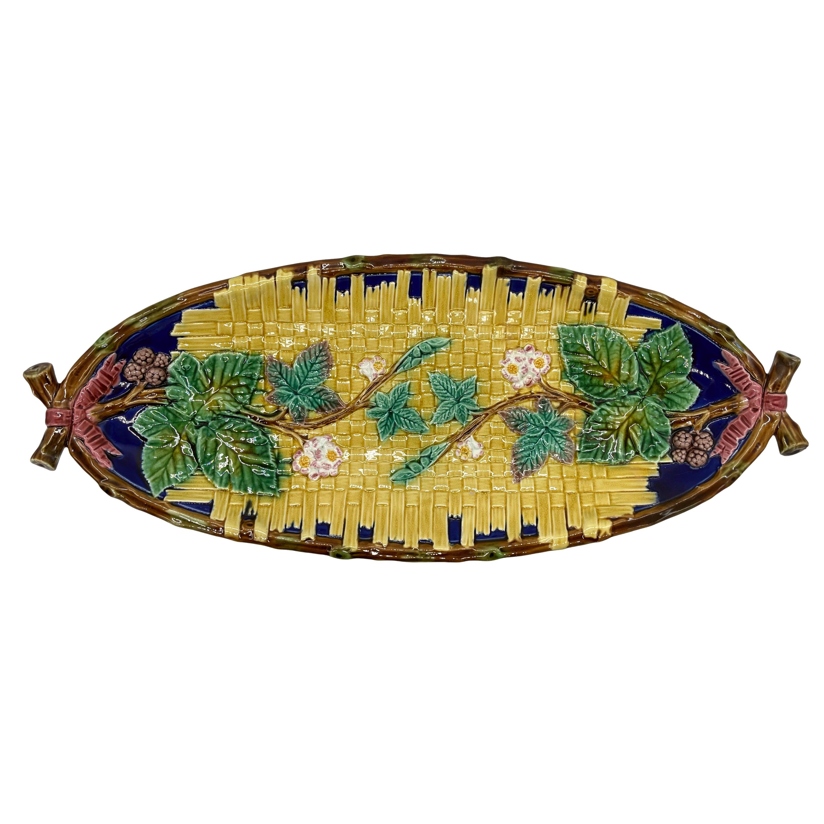 T.C. Brown-Westhead, Moore & Co. Majolica Oblong Tray, molded with a yellow glazed wicker mat with relief molded blackberries, trailing leaves, and blossoms on a cobalt blue ground, the branch form rim crossed and tied at either end with a pink and