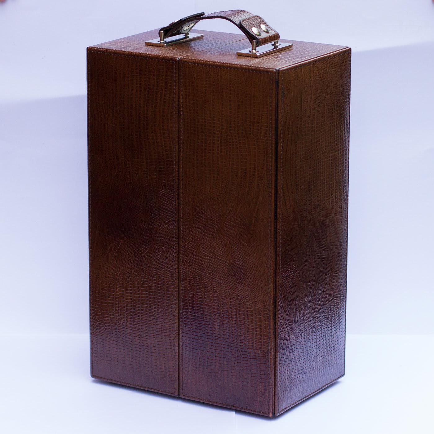 This sophisticated case is elegantly handcrafted of brown leather and features two rectangular metal handles on top. It opens in half with a hinged closure to reveal two storage compartments lined in soft cream-colored suede fitted to contain three