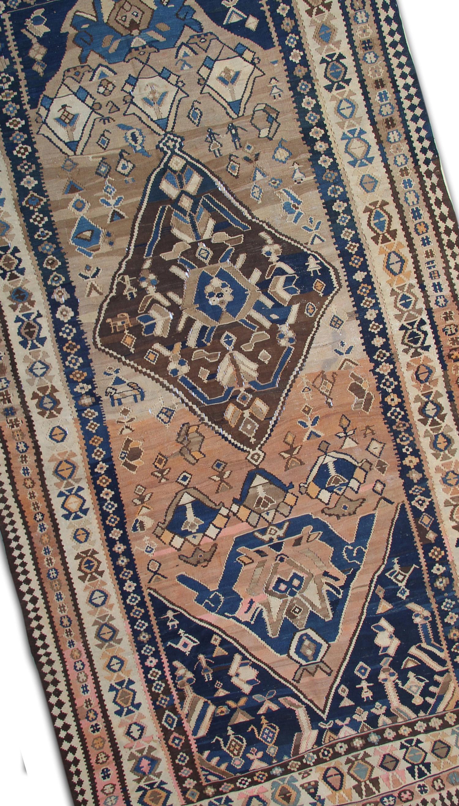This fine wool Kilim is a fantastic example of Kilims woven in the 1890s. The design features a bold medallion woven in brown with Brown, beige and blue accents. The colour palette is unique, with rustic blue and rust and brown accents. This antique