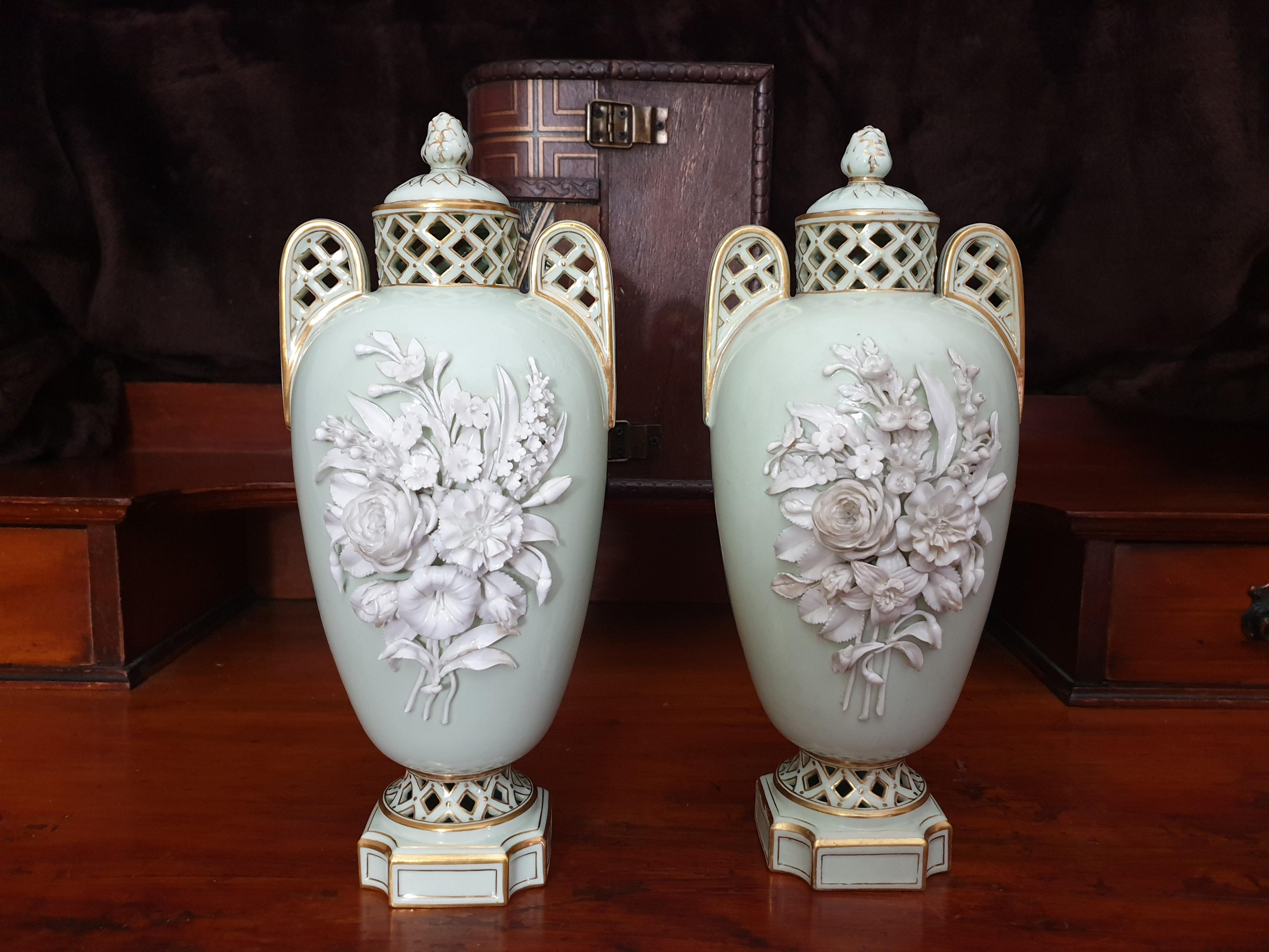 A pair of stunning mint green and floral encrusted lidded vases made by William Brownfield & Co in around circa 1840s in oval form. Two reticulated handles stems from the high pierced neck and highlighted in gilt. The lids are decorated with a leaf