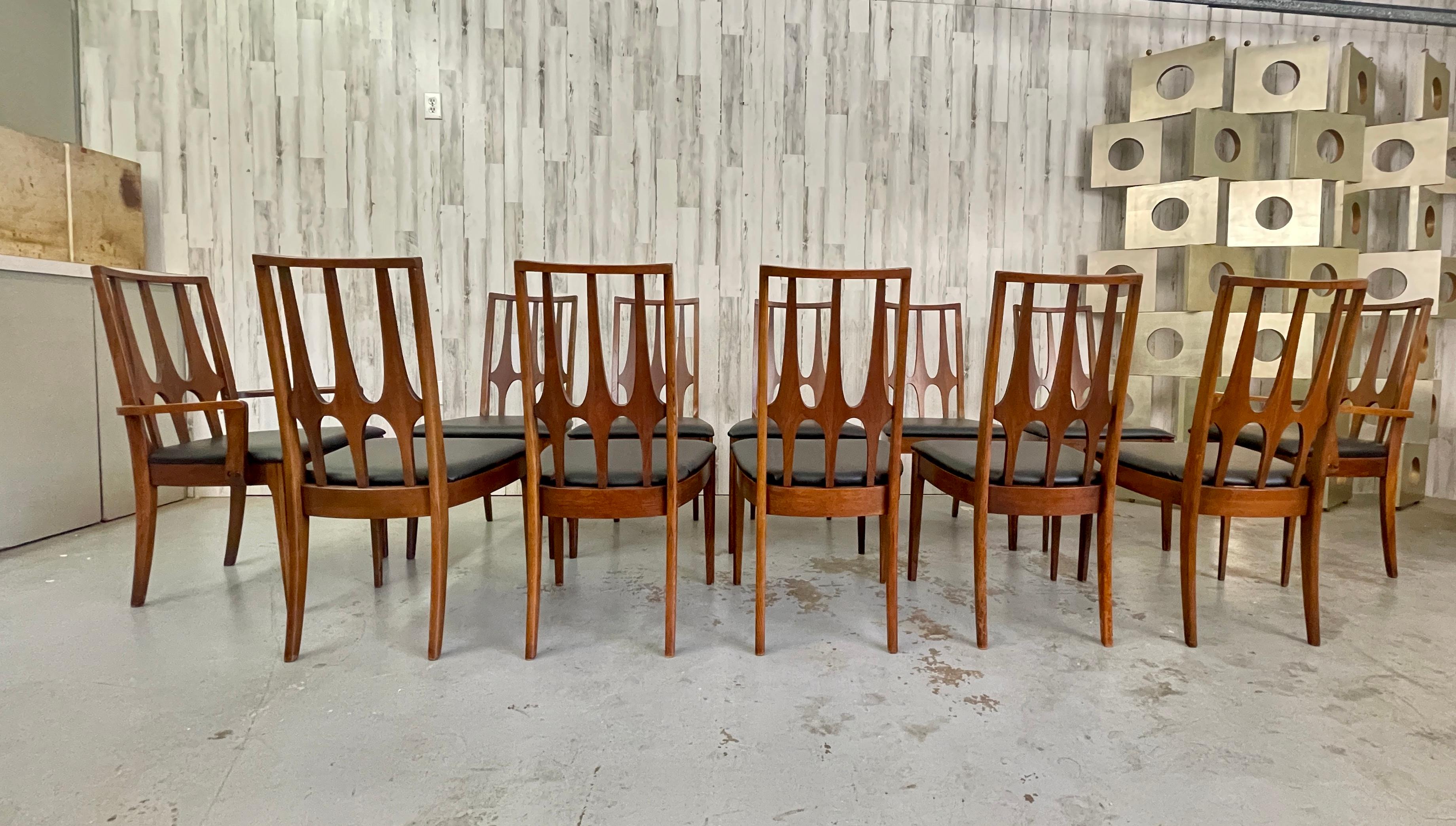 Broyhill Brasilia Dining Chairs- Set of 12 with a new black vinyl upholstery. 10 side chairs and 2 arm chairs. 
Arm Chairs measure: 21.38 W x 22.38 D x 37.63 H Seat: 18.38.