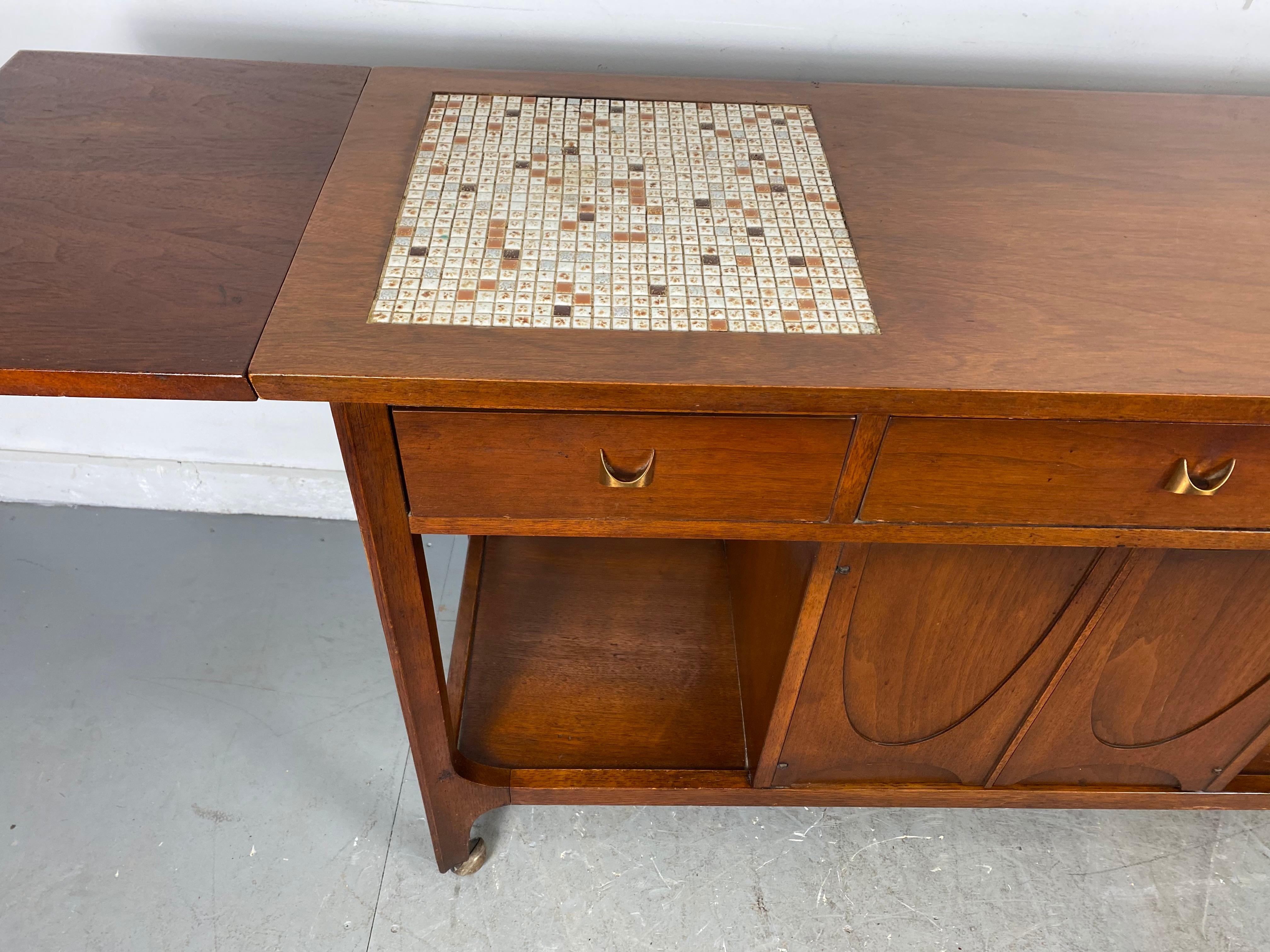 Stunning Broyhill Brasilia drop leaf tile top serving bar cart console table. Retain's it's original period mosaic tiles-. This versatile piece has cabinet space for bottles underneath as well as drawer space to suit all your storage needs. Divided