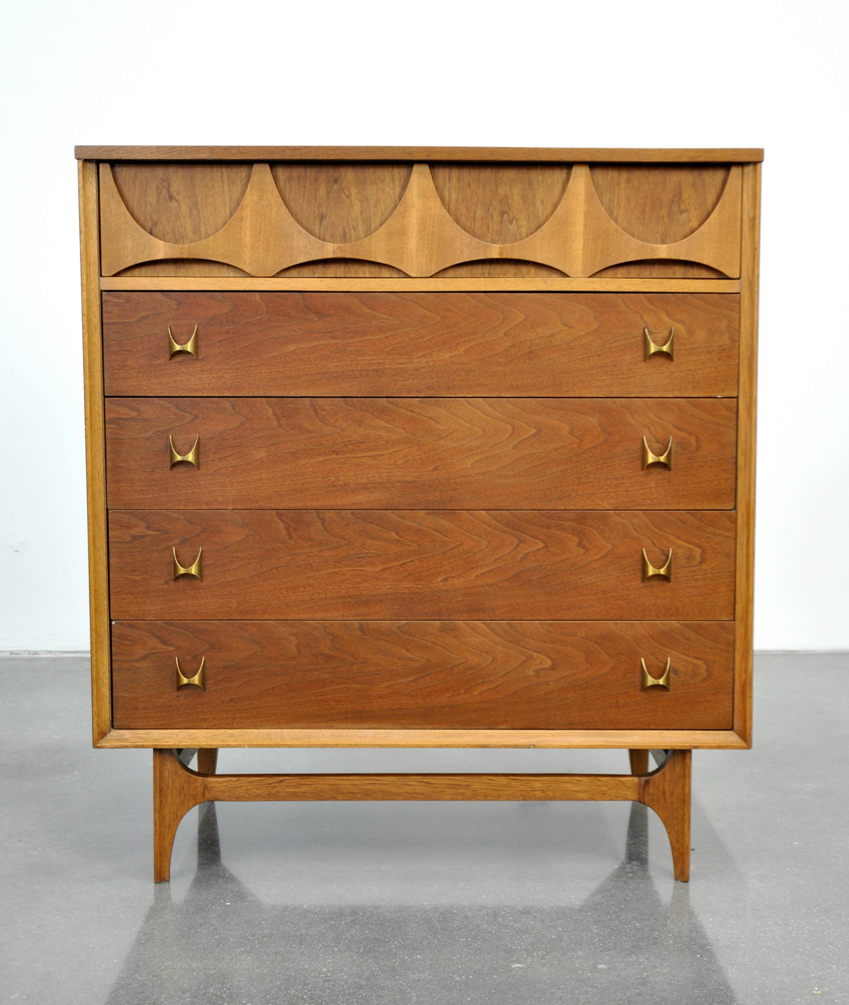 A vintage Mid-Century Modern walnut and brass chest of drawers from the highly desirable Brasilia collection manufactured by Broyhill in the 1960s. The bachelor or gentleman's chest's top drawer features the signature relief cut and sculpted pattern